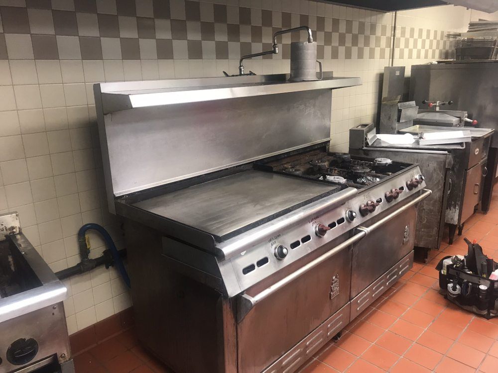 a large stainless steel stove is sitting in a kitchen .GRE