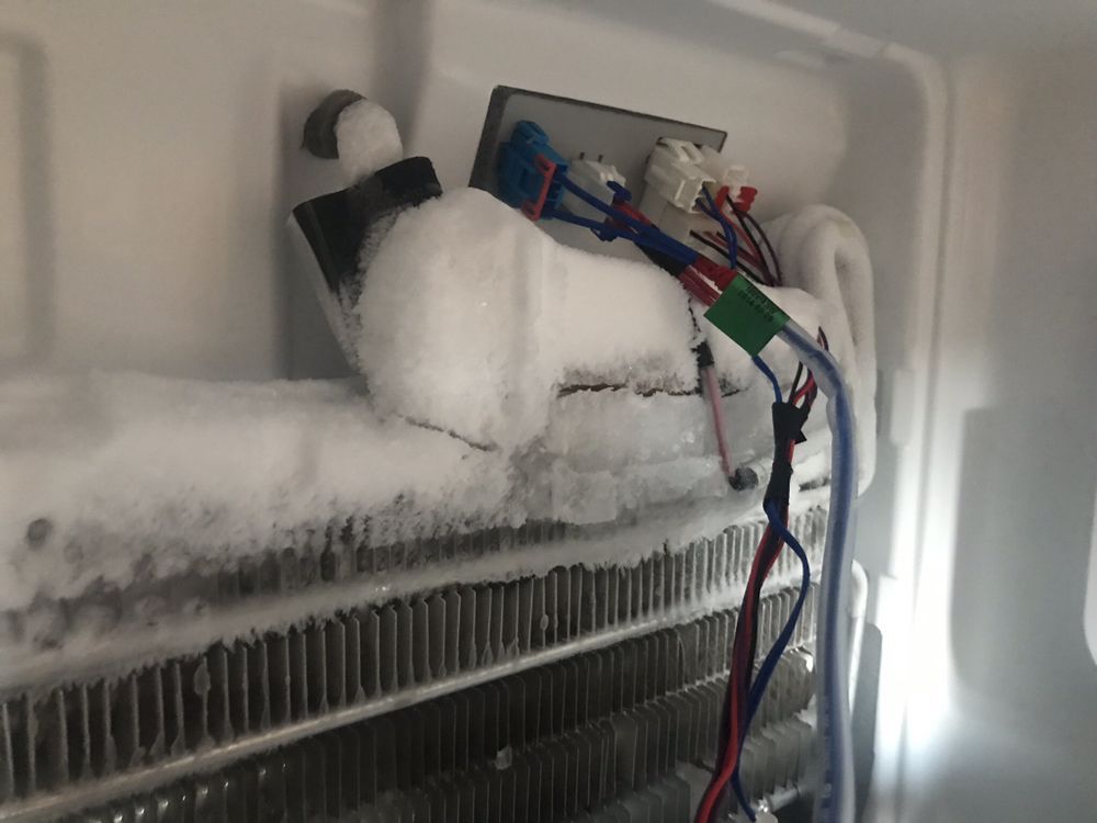 the inside of a refrigerator with a lot of ice on it .