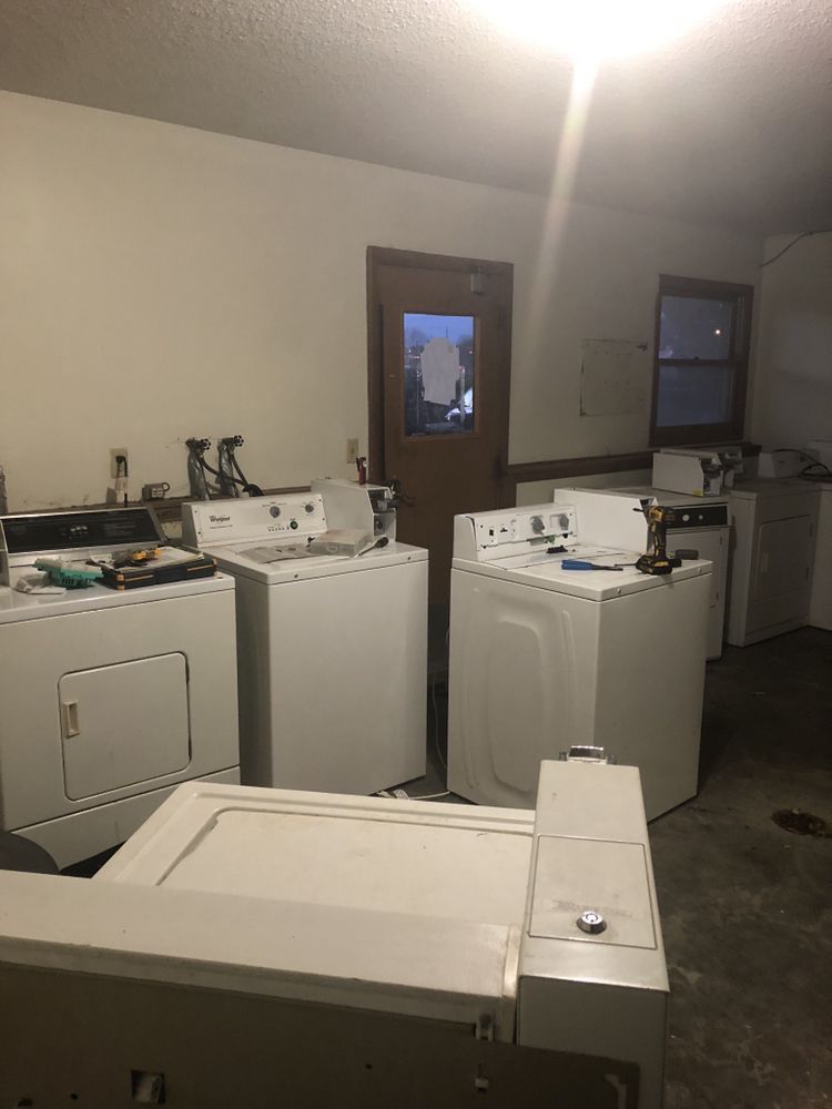 a row of white washers and dryers in a laundry room