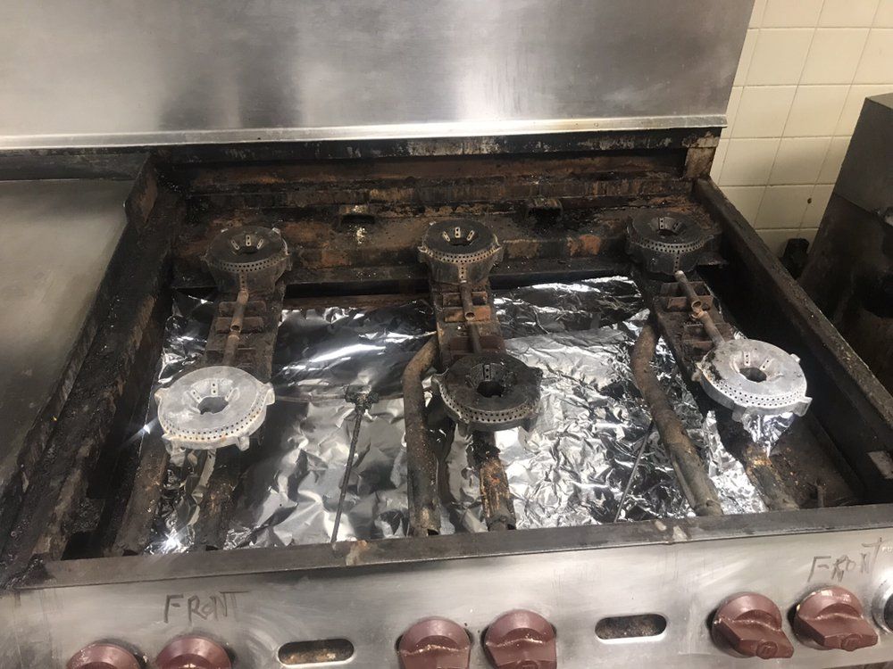 a stove with a lot of burners and aluminum foil on it