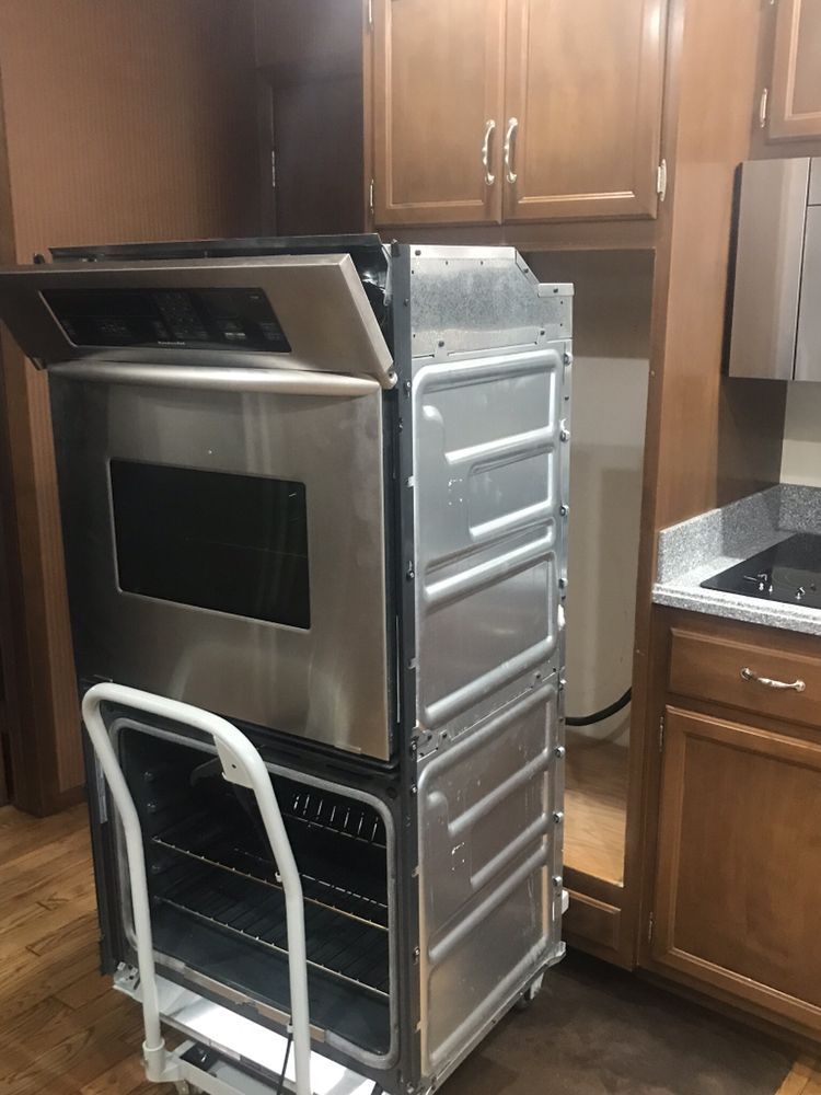 a stainless steel oven is sitting on a cart in a kitchen .