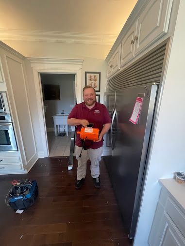 a man is standing in a kitchen holding an orange object .