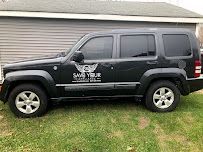 a black jeep is parked in the grass in front of a garage .