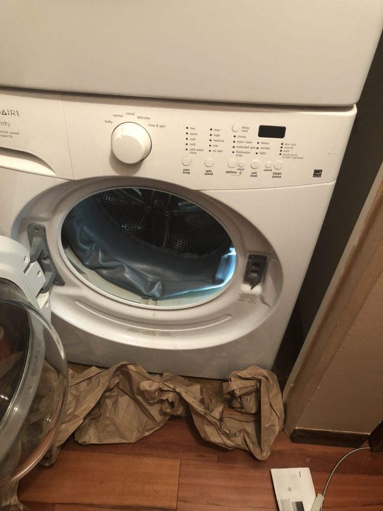 a washer and dryer are stacked on top of each other on a wooden floor .