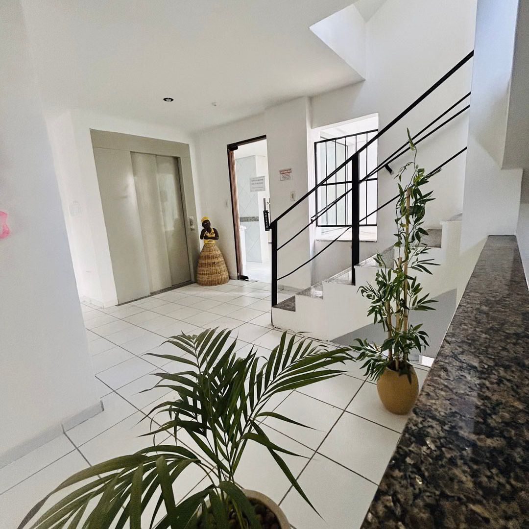 Uma planta em vaso está em um corredor ao lado de uma escada.