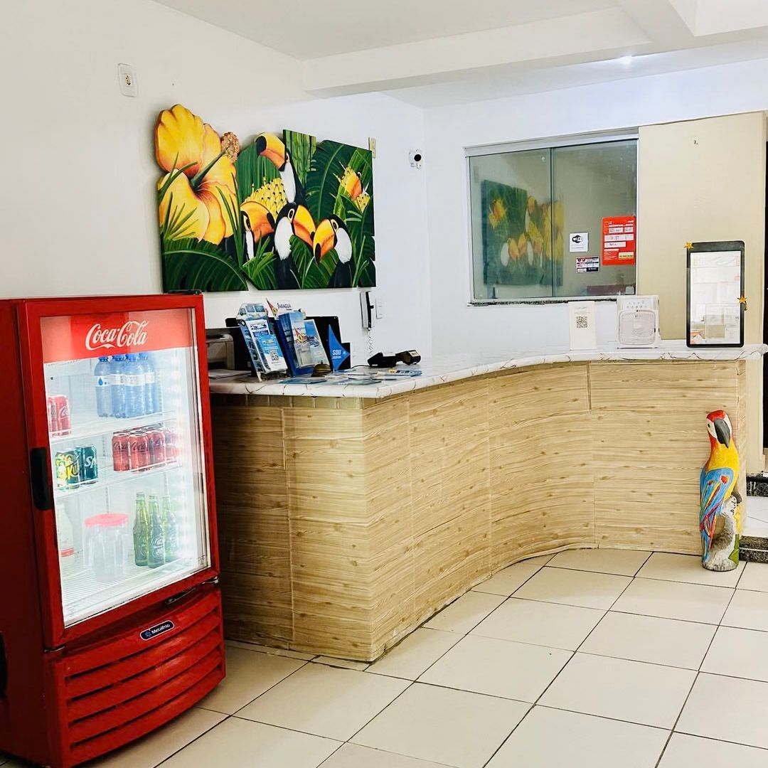 Uma geladeira vermelha da Coca-Cola está ao lado de um balcão em uma sala.