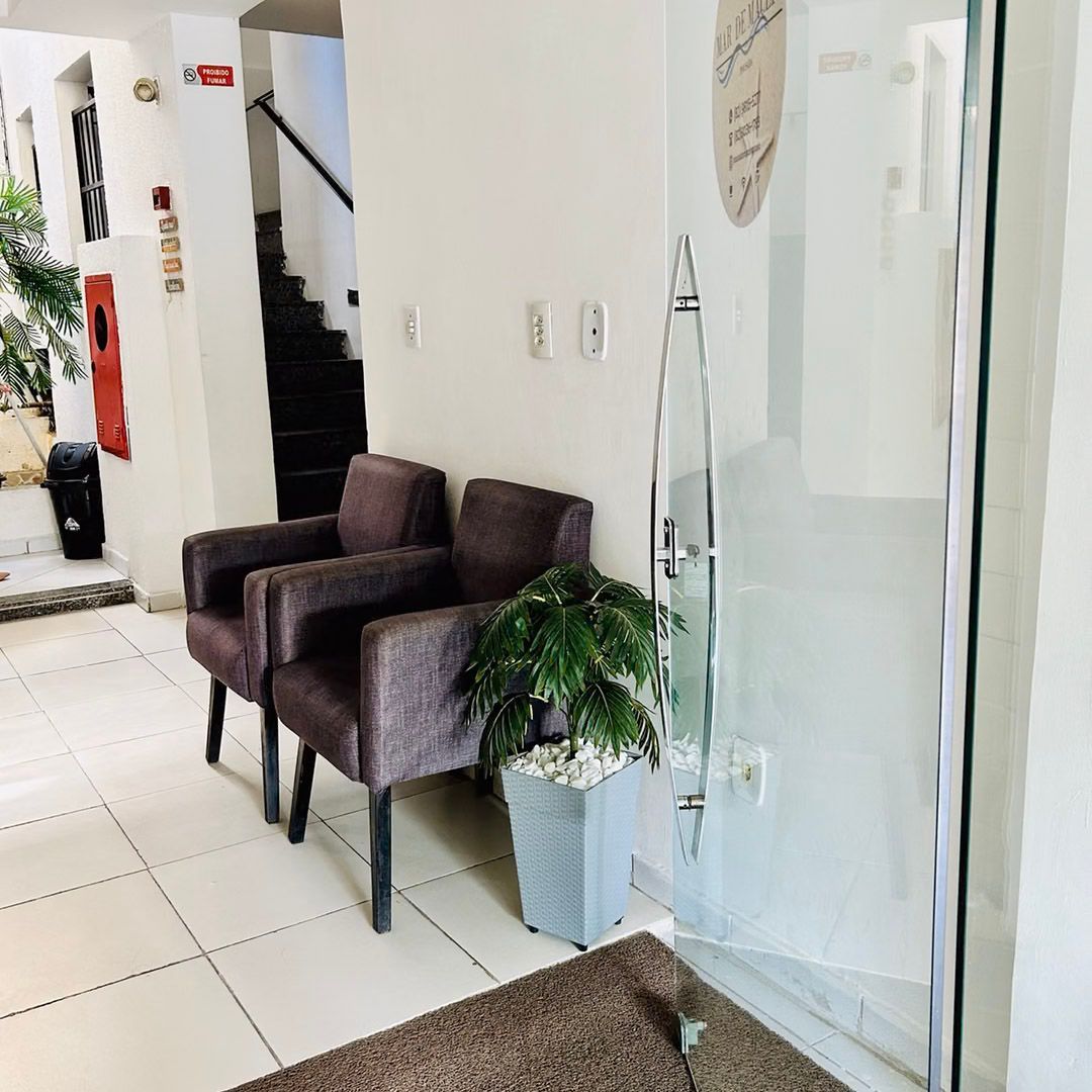 Uma sala de espera com duas cadeiras e um vaso de planta