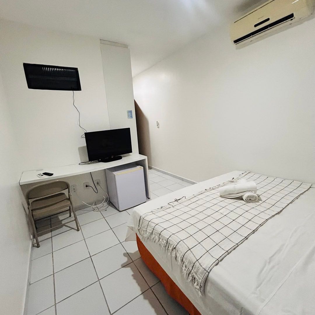 Um quarto de hotel com uma cama, uma escrivaninha e uma televisão