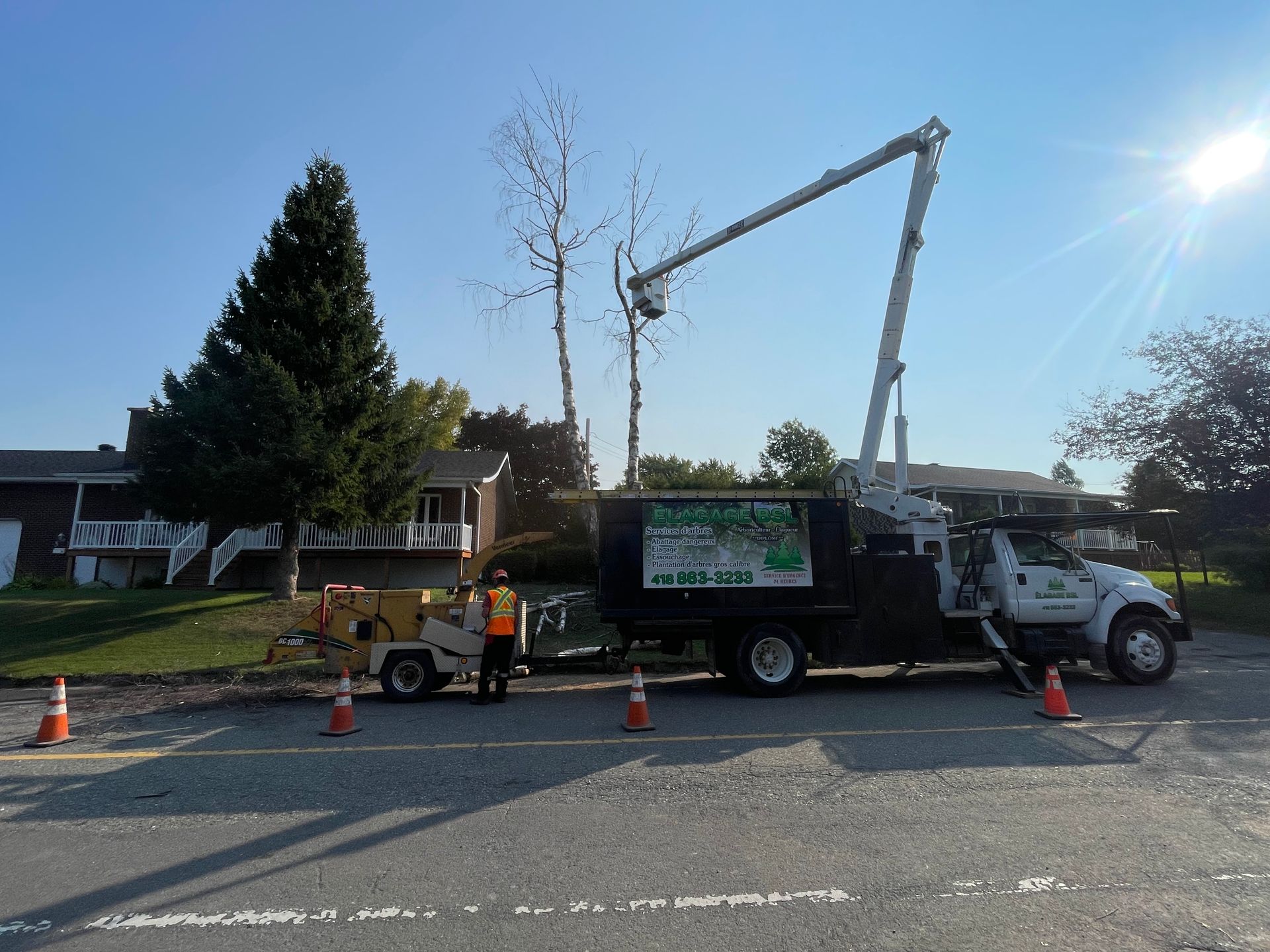 Un camion d'élagage d'arbres est garé sur le bord de la route