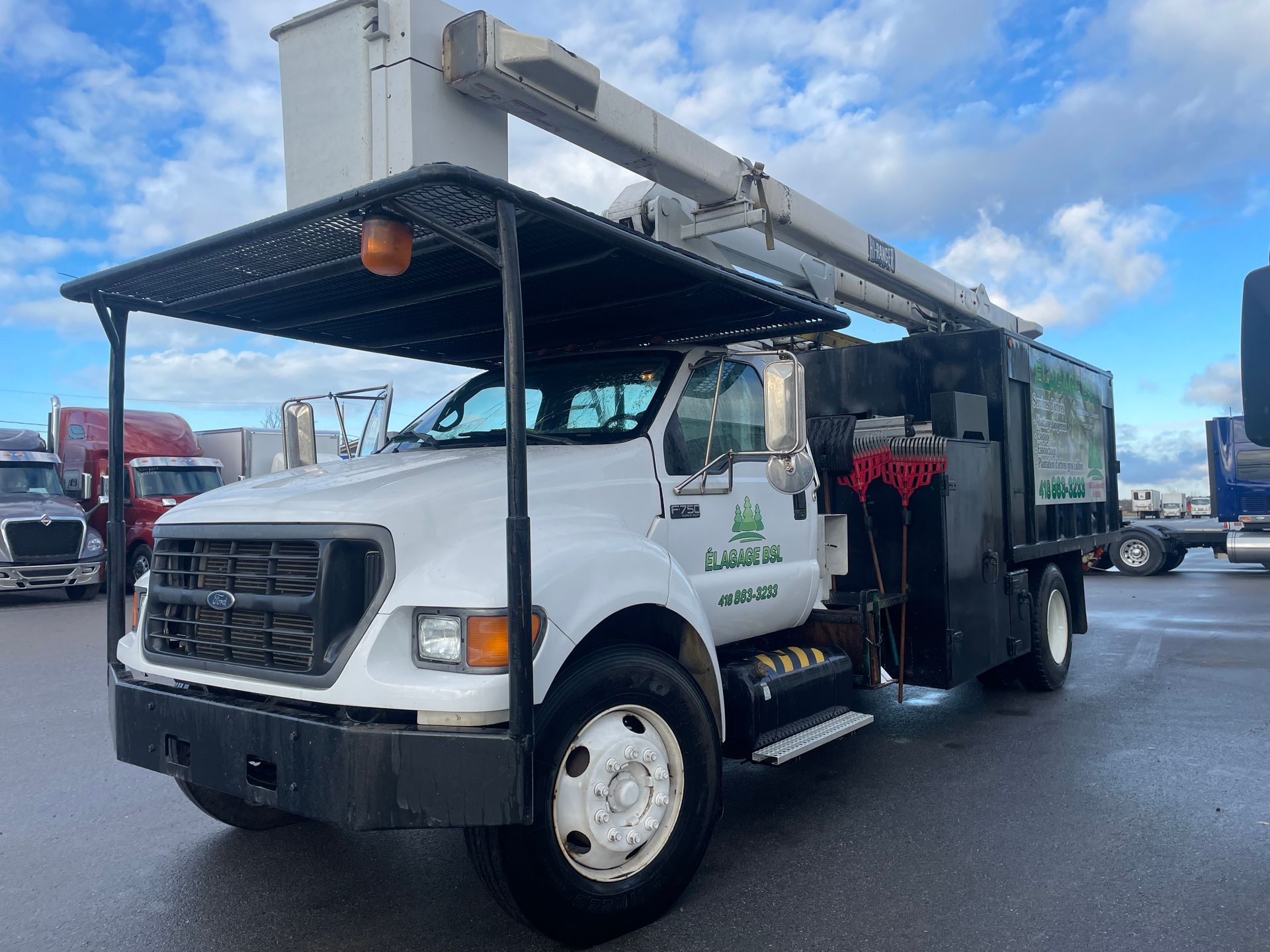 Un camion blanc avec une grue dessus est garé sur un parking.