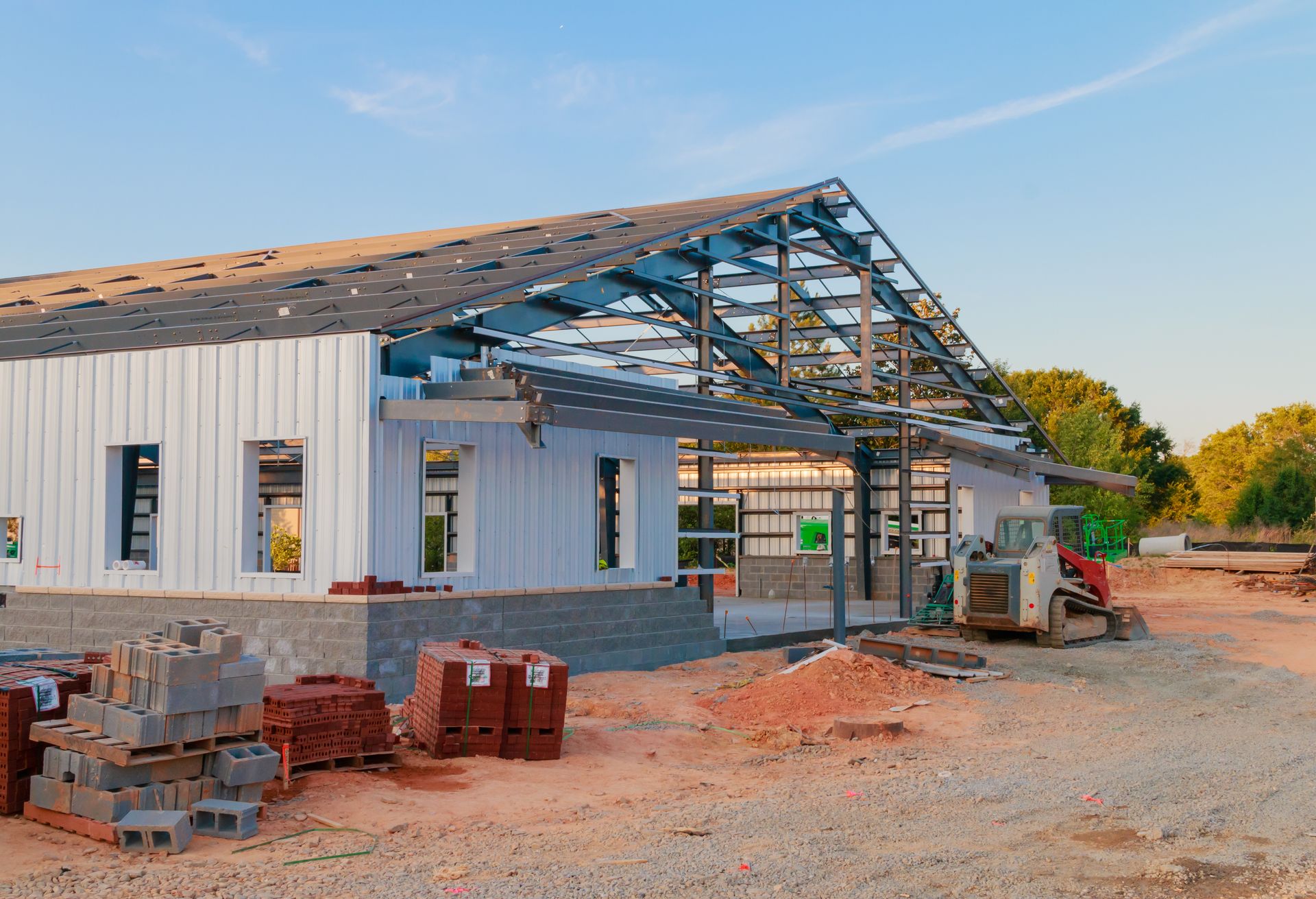 Metal building under construction with steel frame and siding being installed.