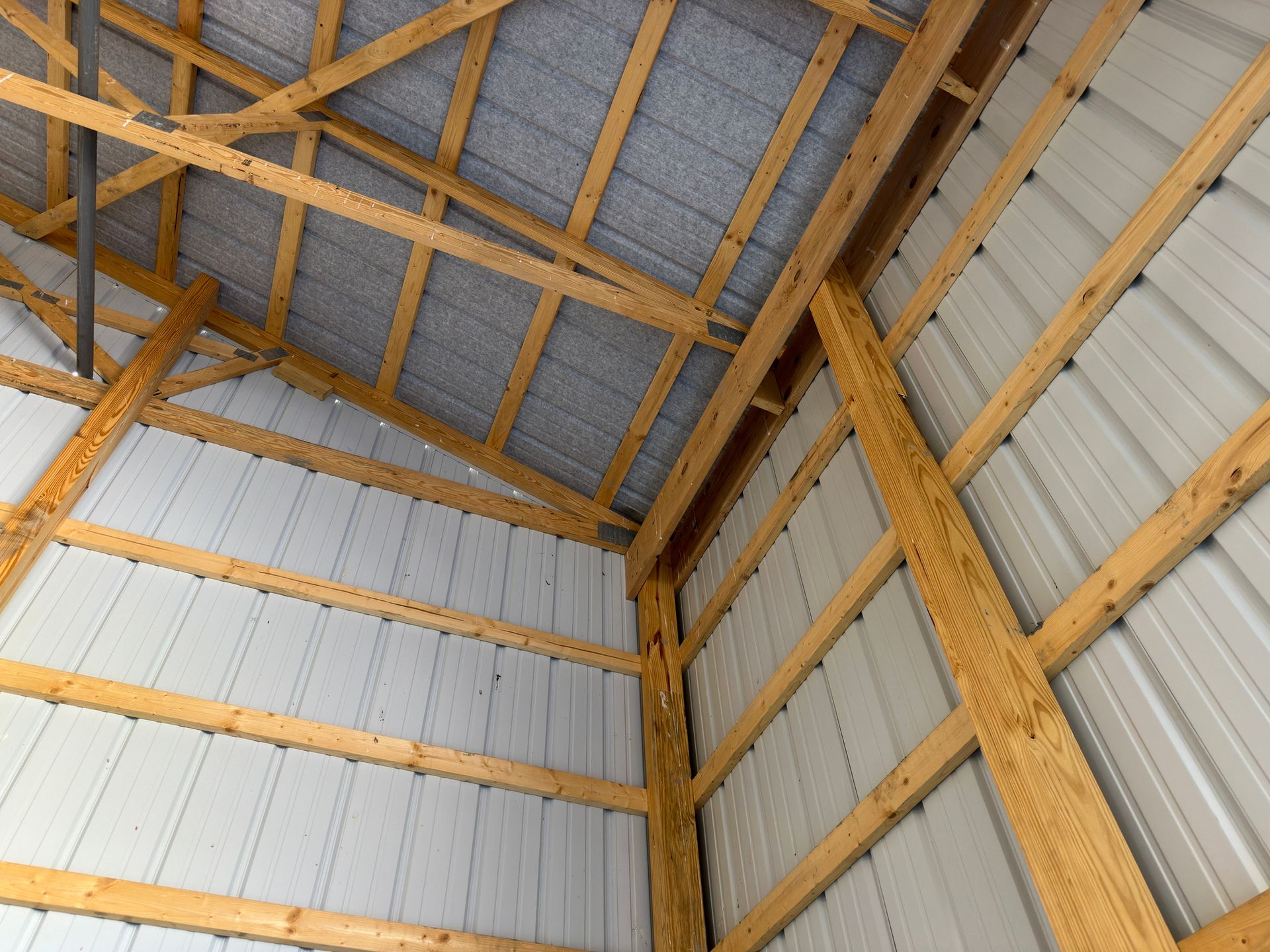 Wood-framed barn interior with metal roof and diagonal supports.