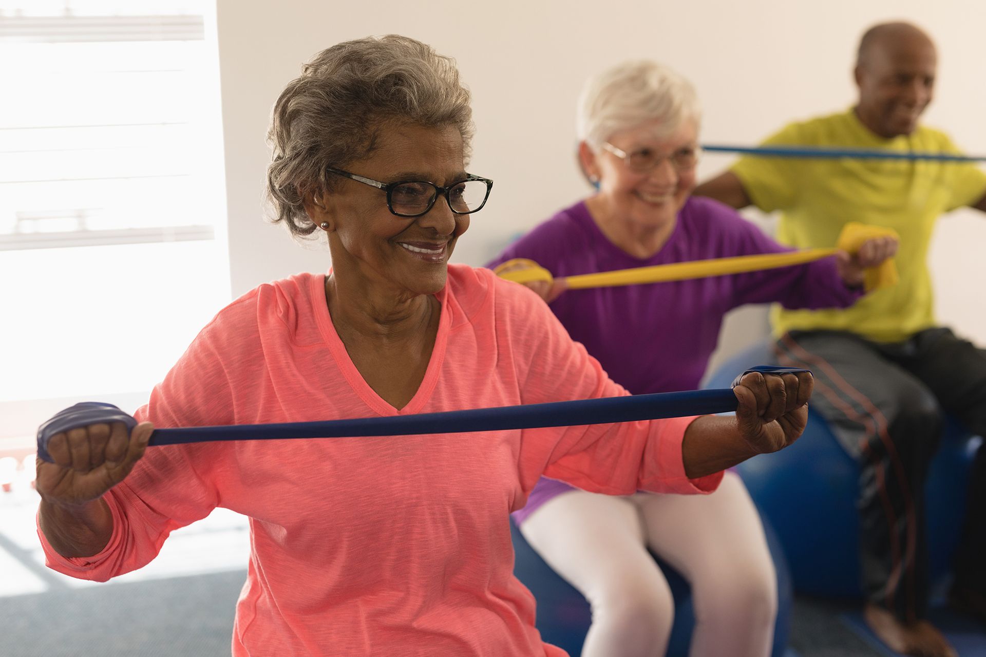 A group of elderly people are doing exercises with resistance bands in a gym