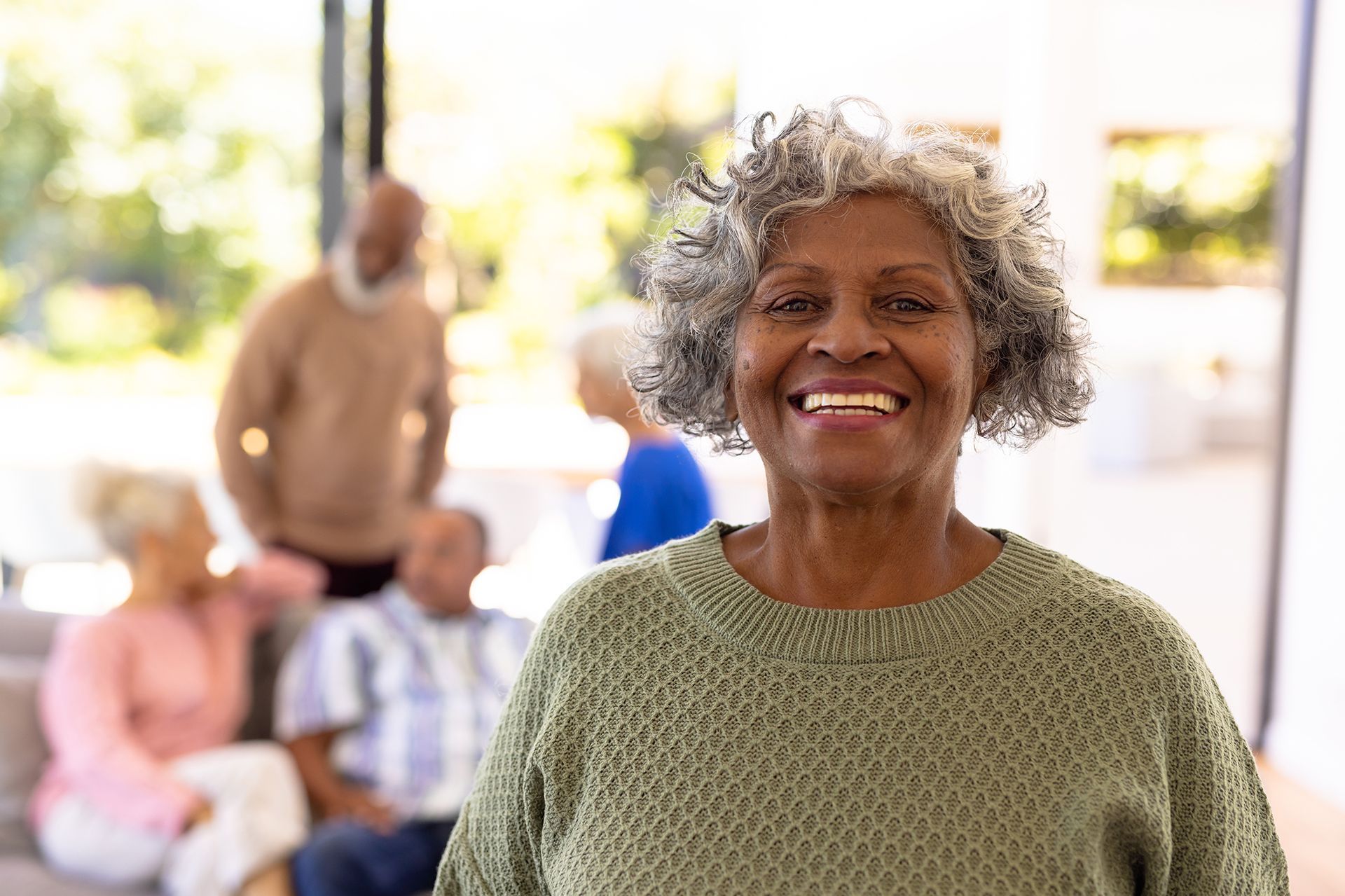 An elderly woman is smiling in front of a group of older people