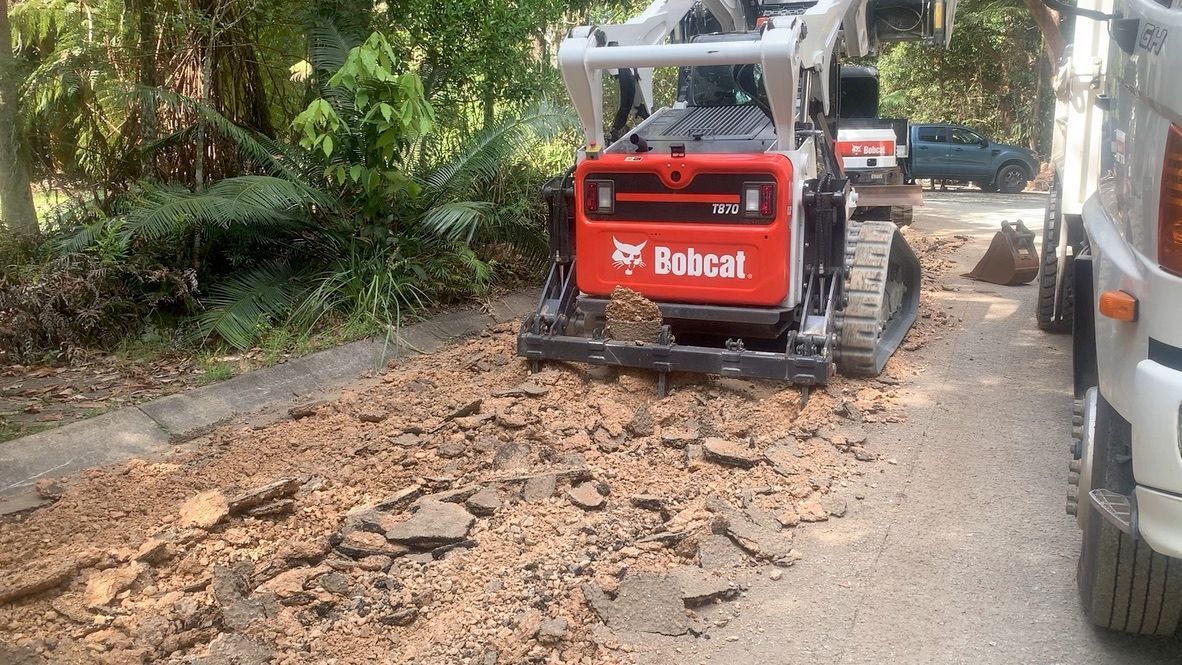 Bobcat Skid-steer Loader on a Torn-up Asphalt Road — Asphalt & Concreting Services & Solutions in Logan Village, QLD

