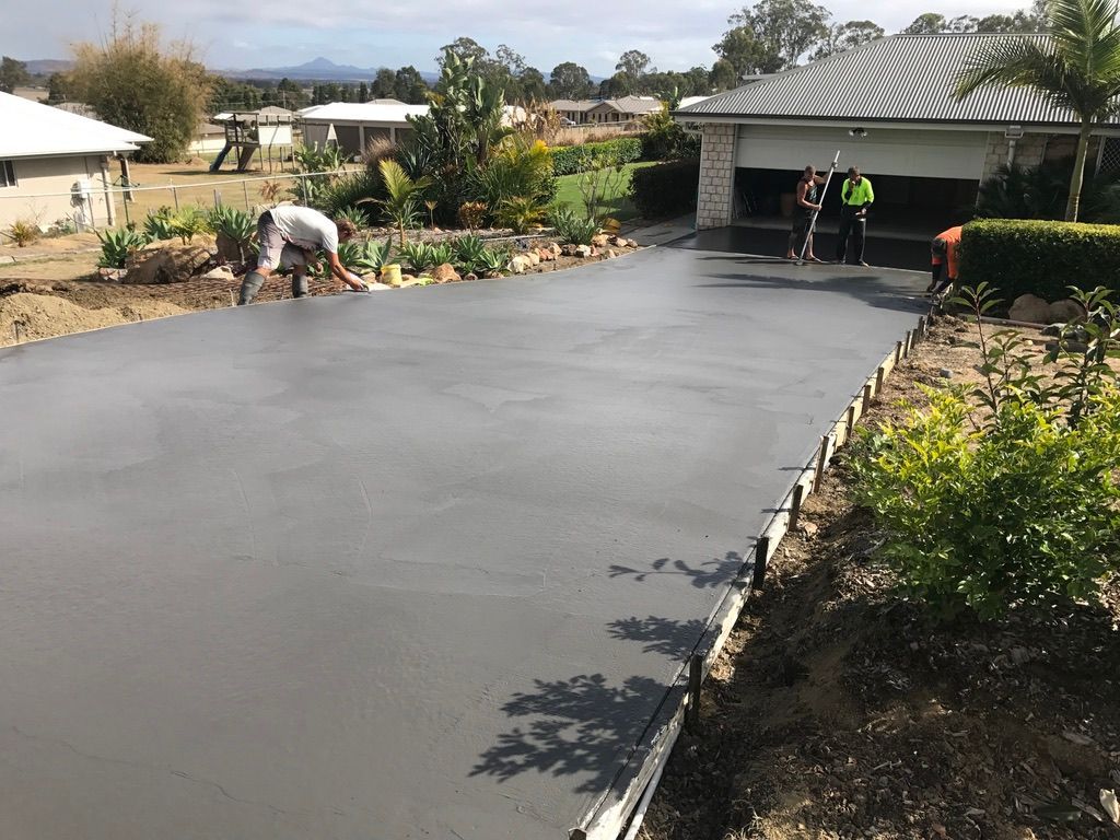 Newly Poured Gray Concrete Driveway With Workers — Asphalt & Concreting Services & Solutions in Logan, QLD