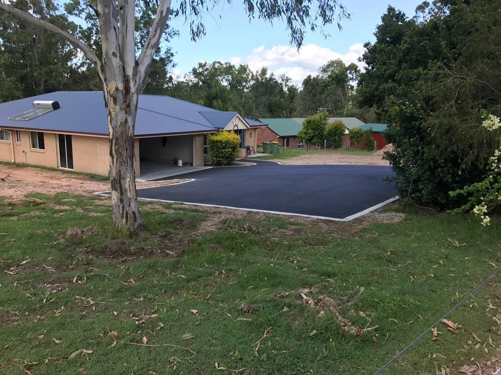 A Paved Driveway in Front of a Brick Building — Asphalt & Concreting Services & Solutions in Logan Village, QLD