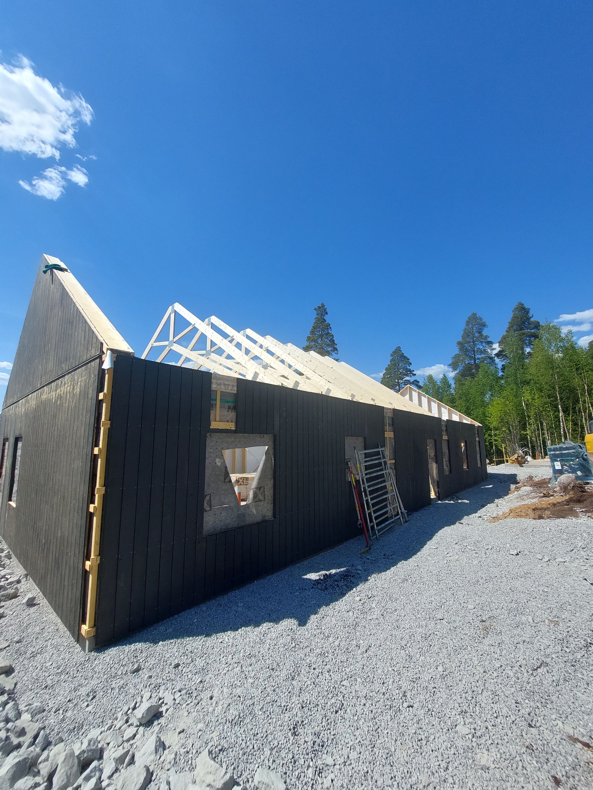 Ett stort hus byggs på en grusväg.