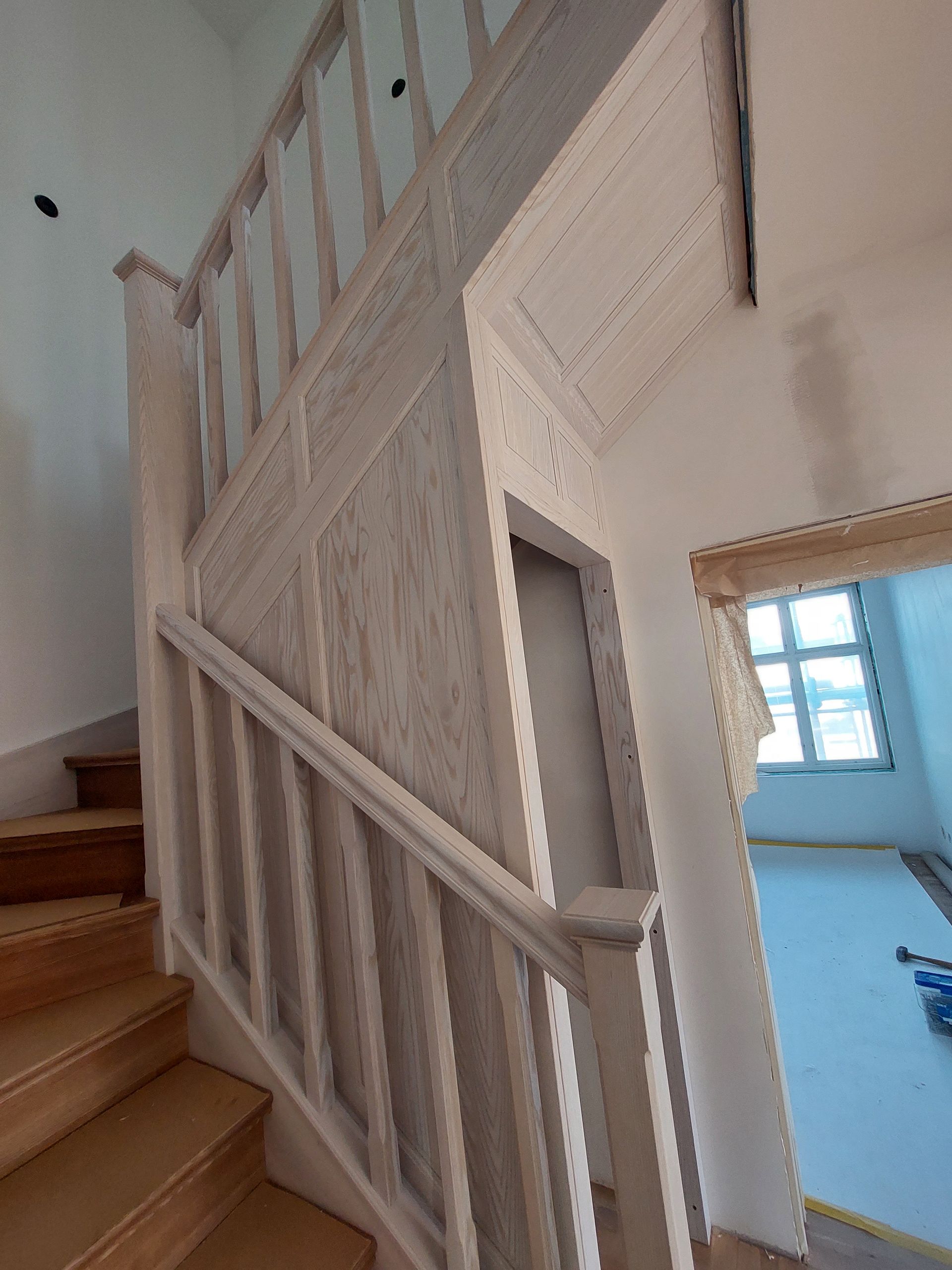 En trätrappa med ett vitt räcke och ett fönster