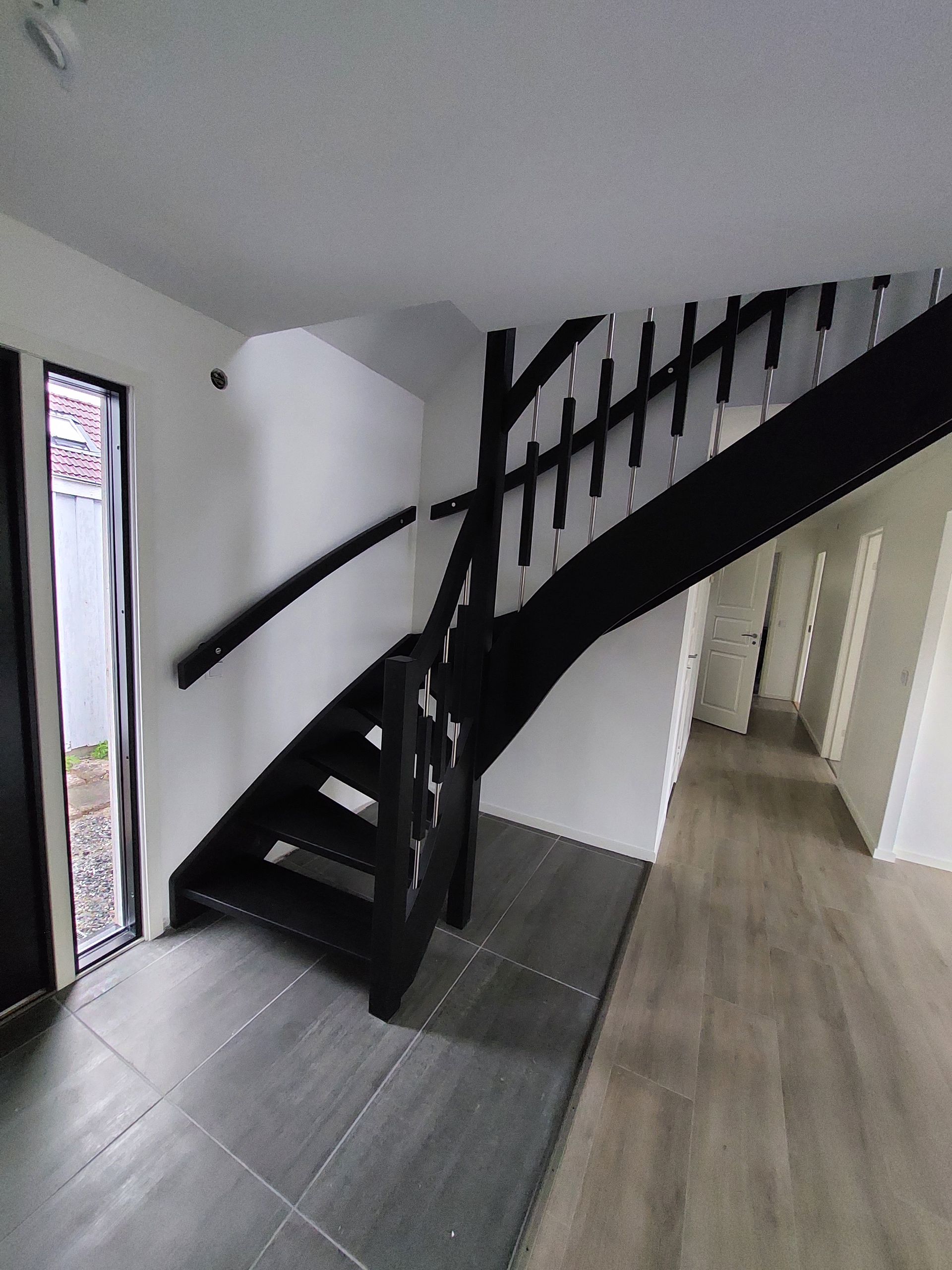 En svart trappa leder upp till andra våningen i ett hus.