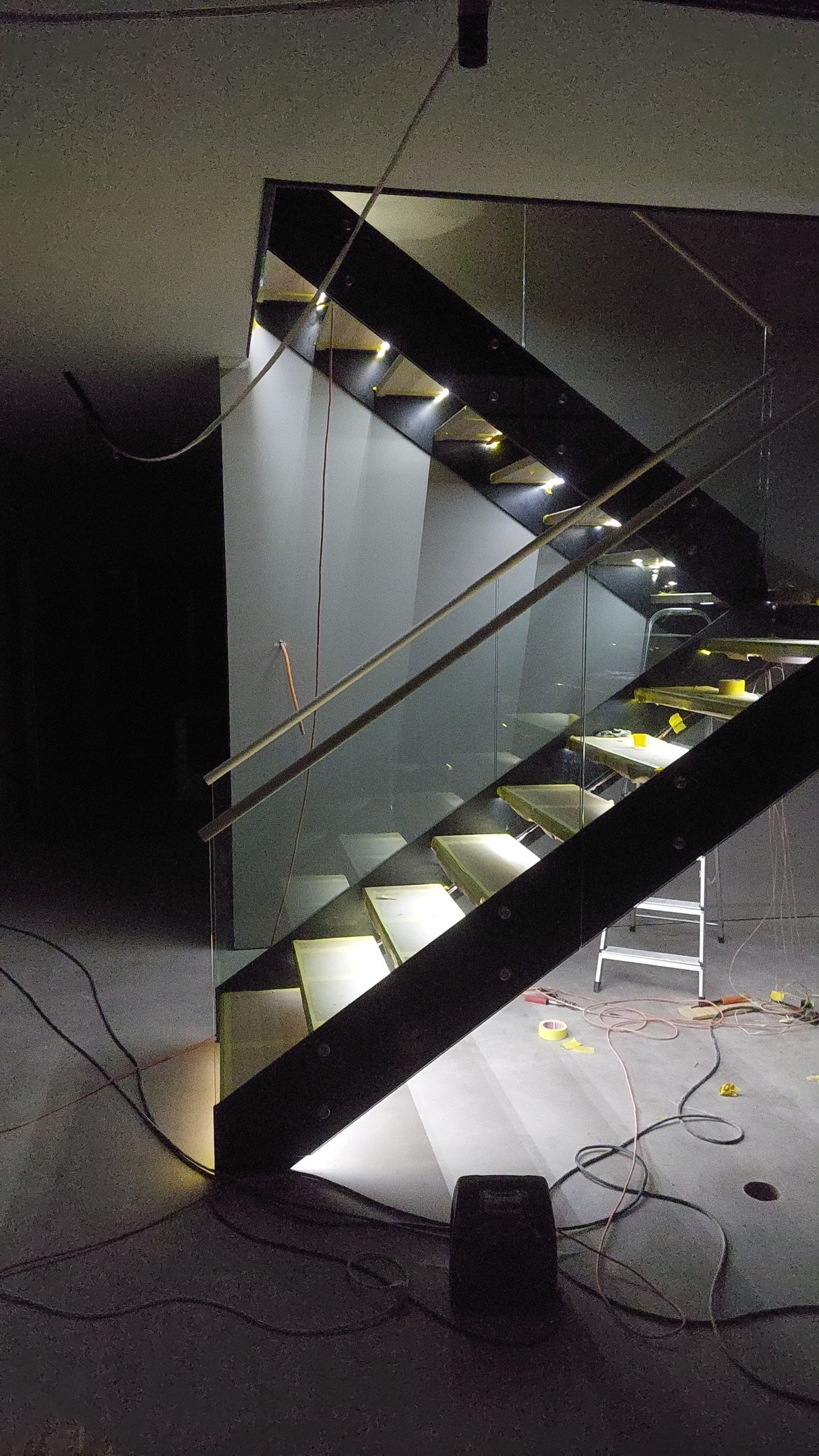 En trappa med glasräcke lyser upp på natten.