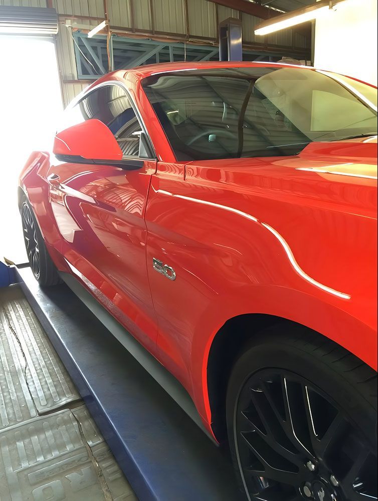 A Red Mustang is Sitting on a Lift in a Garage — Endrust (Coffs Harbour) in Coffs Harbour, NSW