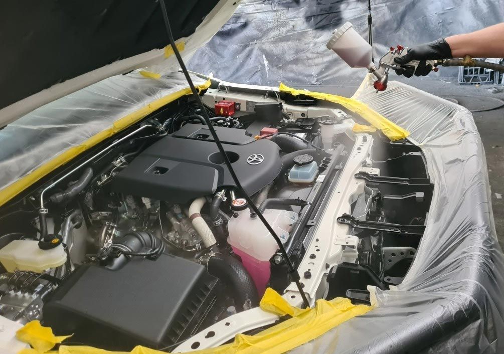 A Person is Spraying Paint on the Engine of a Car — Endrust (Coffs Harbour) in Coffs Harbour, NSW