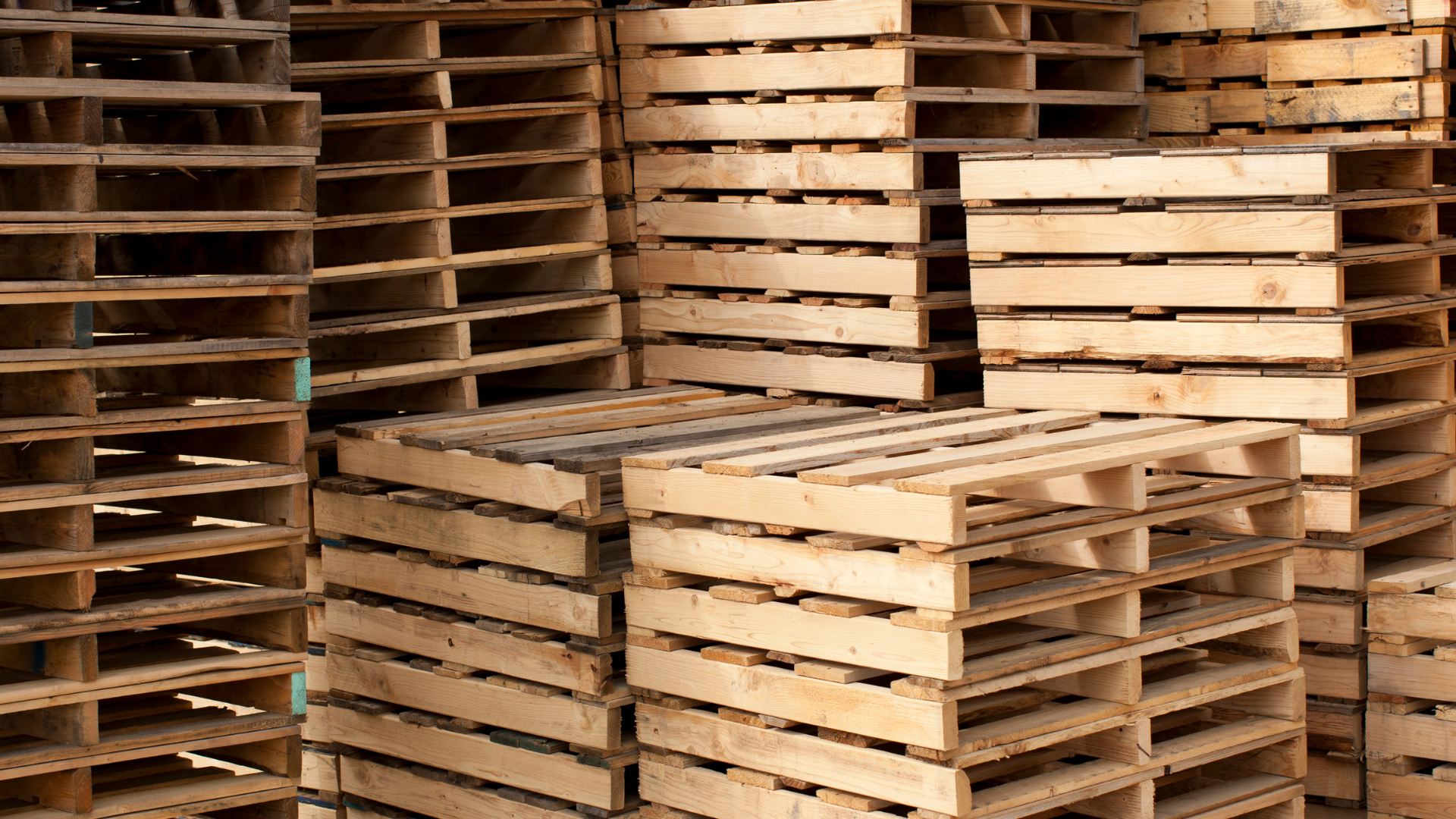 A pile of wooden pallets are stacked on top of each other.