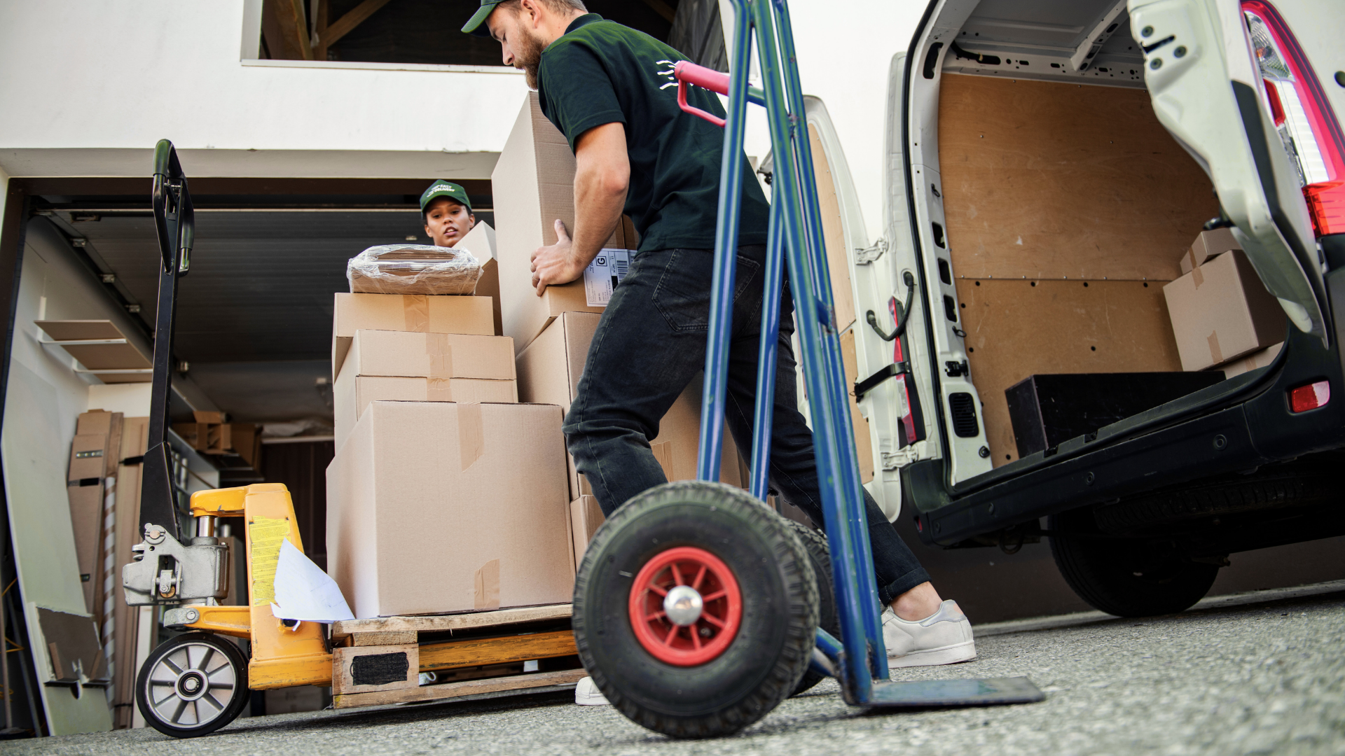 A man is pushing a cart full of boxes into a van.