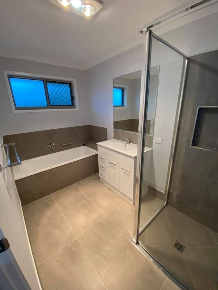 A Modern Bathroom with A Bathtub, Shower, Vanity, and Window — Country to Coast Homes In Gregory River, QLD