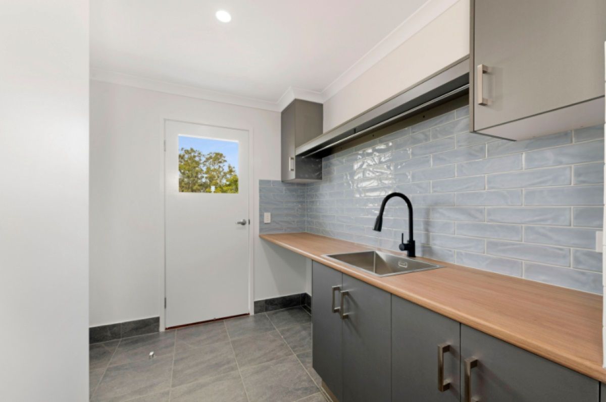 Laundry Room with Gray Cabinets, Blue Tiled Backsplash — Country to Coast Homes In Bundaberg, QLD