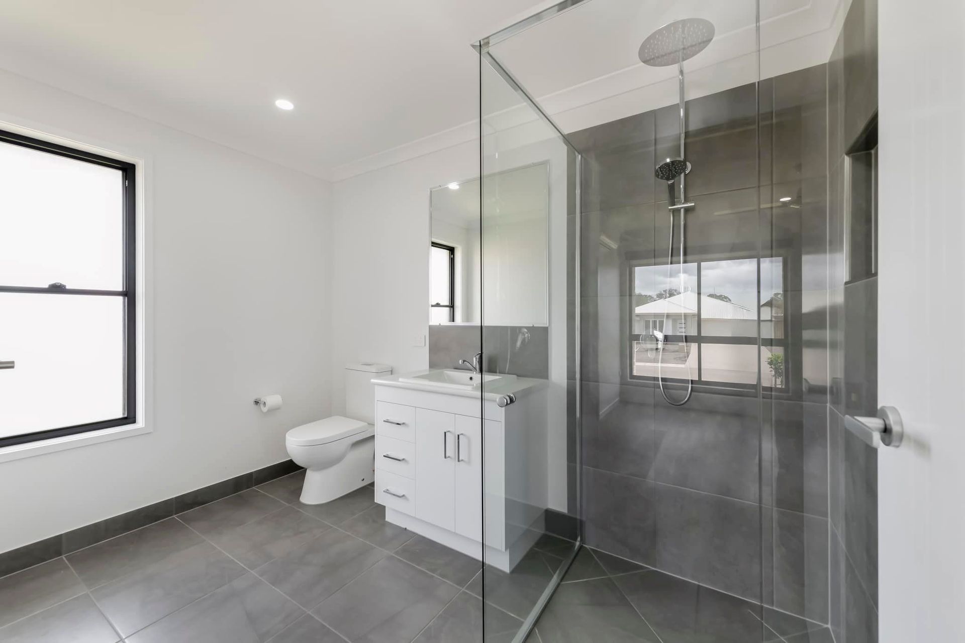 Modern Bathroom with Gray Tiled Floor and Shower — Country to Coast Homes In Woodgate, QLD
