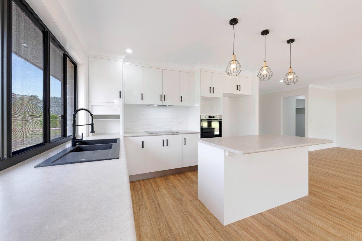 Modern White Kitchen with Island, Black Faucet, and Pendant Lights — Country to Coast Homes In Childers, QLD