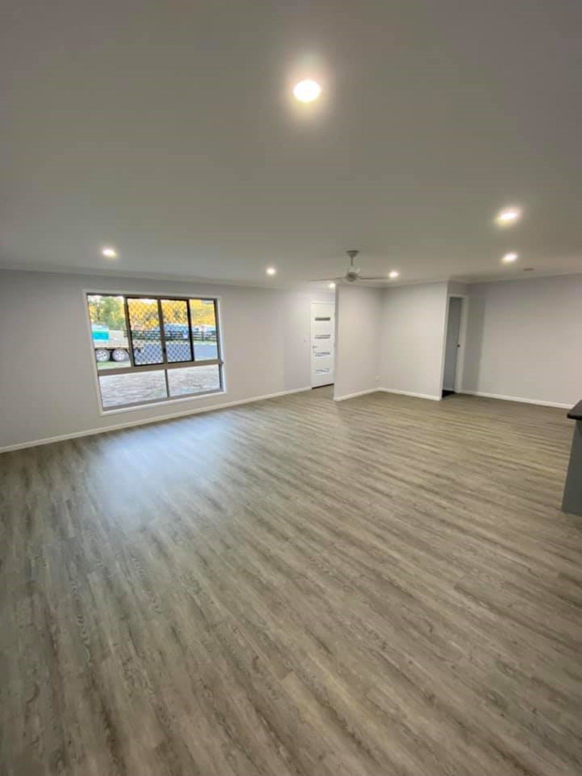 Spacious, Empty Room with Light Gray Walls and Wood-Look Flooring — Country to Coast Homes In Woodgate, QLD
