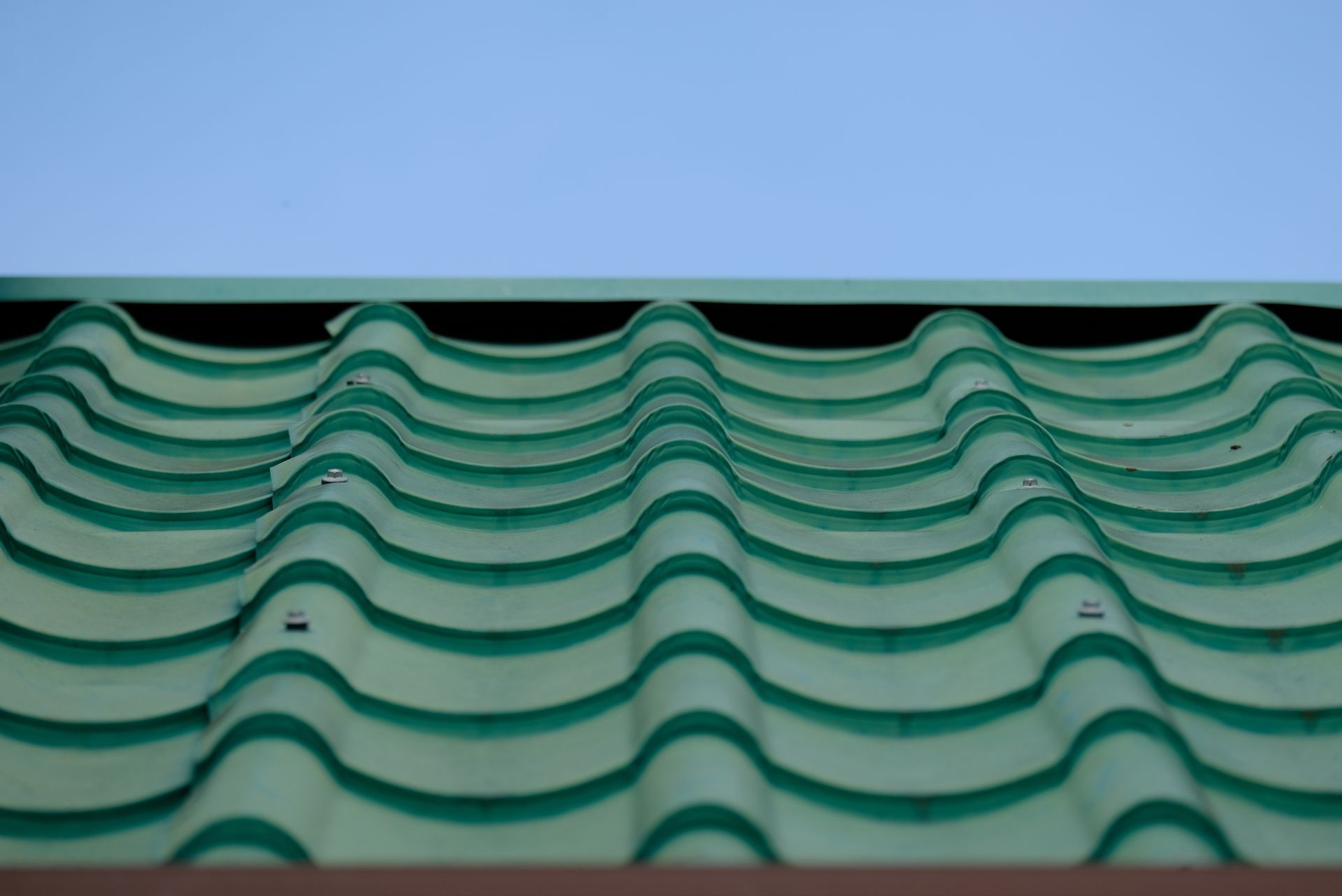 Green corrugated metal roof against a clear blue sky