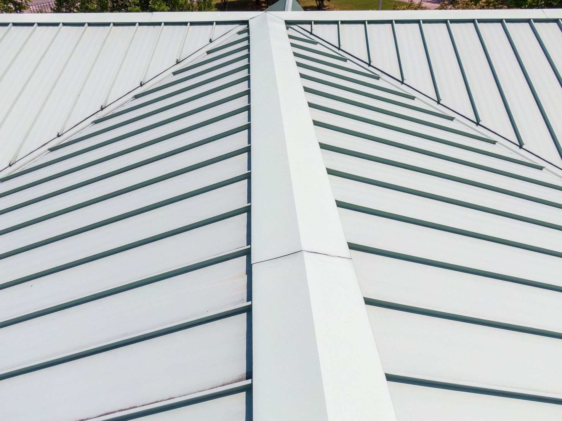 White metal roof with a central ridge and evenly spaced seams, viewed from below