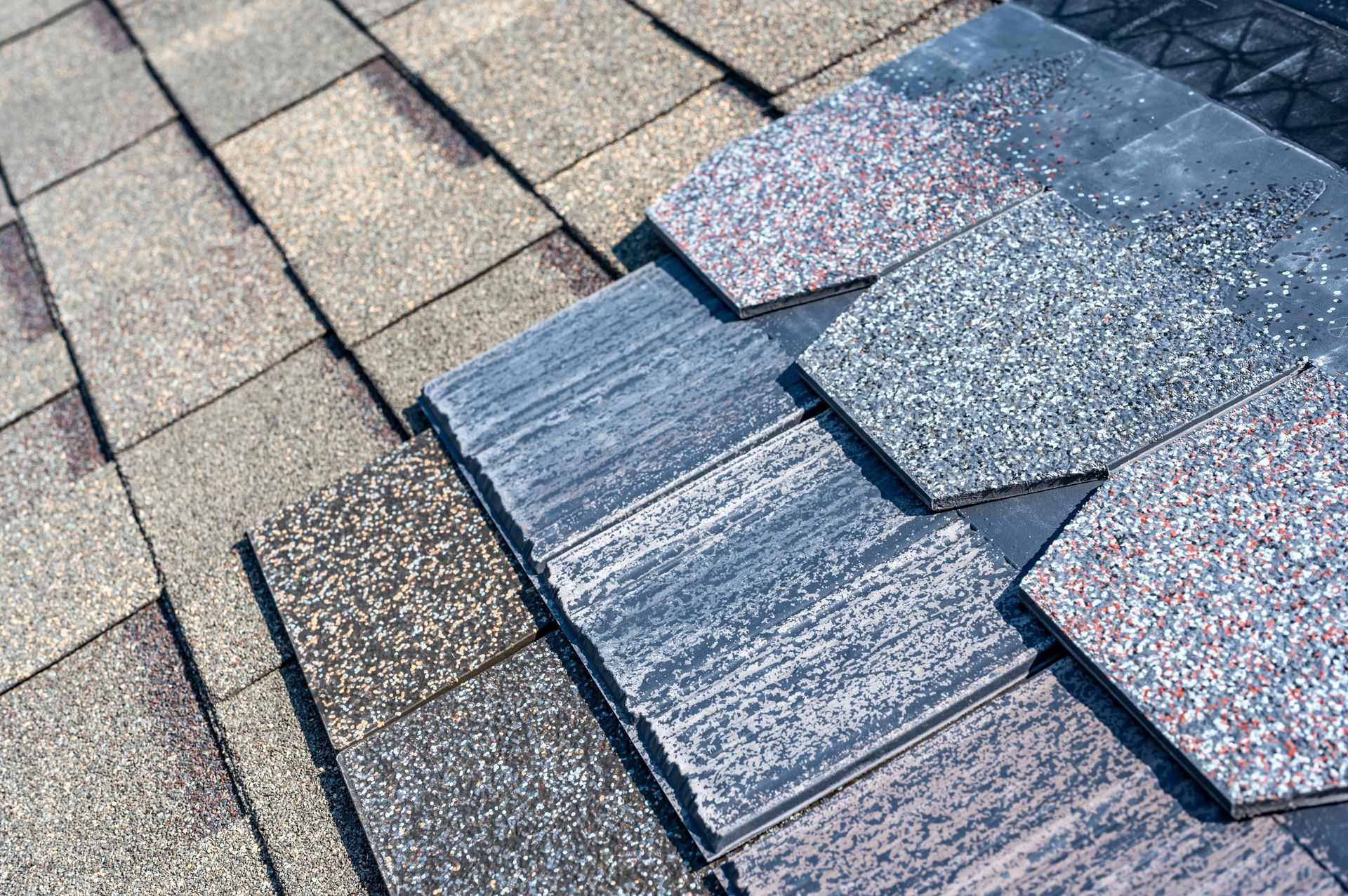 Damaged asphalt roof shingles with a patch of newer, darker shingles on the right