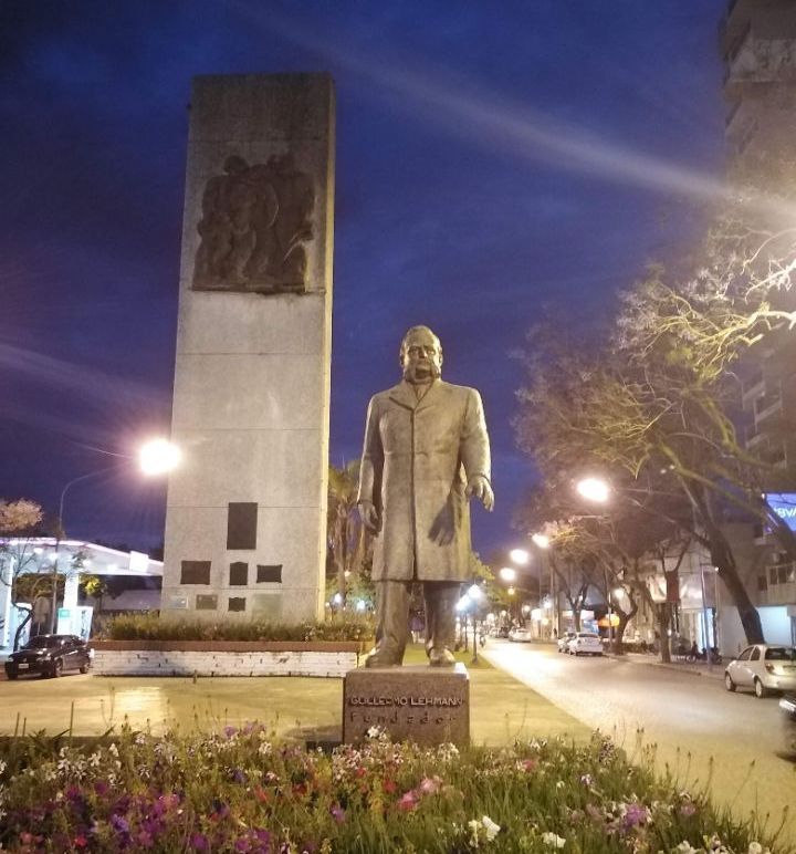 A statue of a man in a trench coat is in front of a tall building