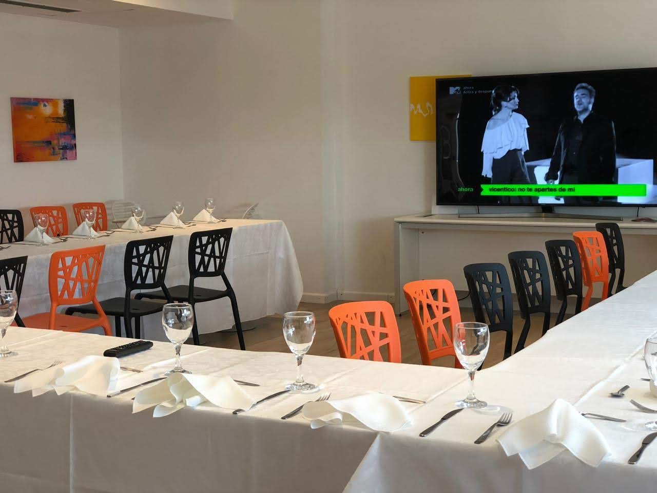 A conference room with tables and chairs and a flat screen tv