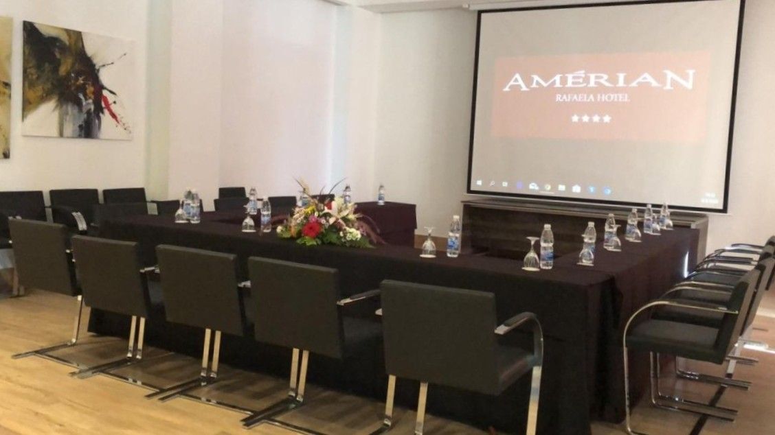 A conference room with a long table and chairs and a projector screen.