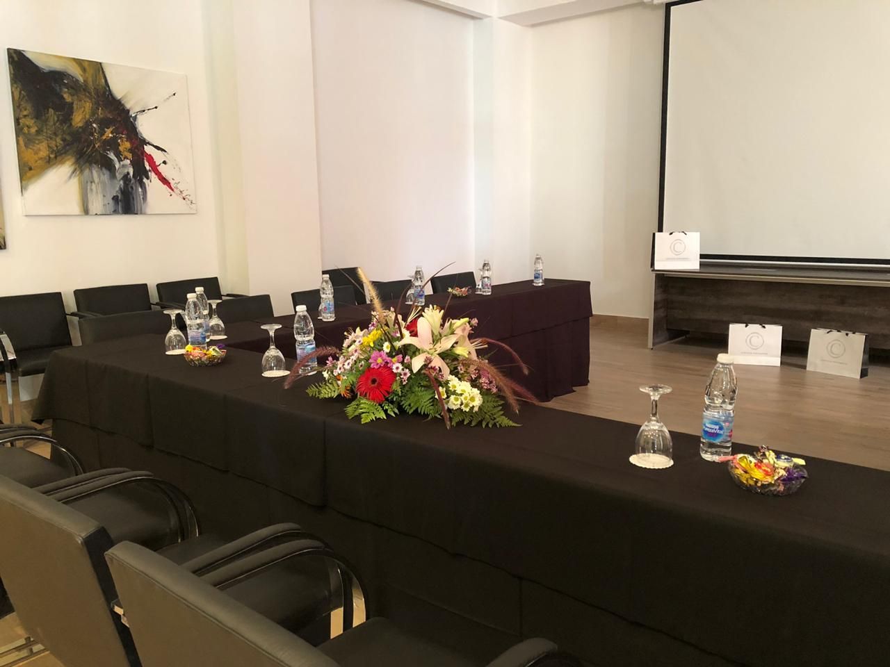A conference room with a long table and chairs and a projector screen.