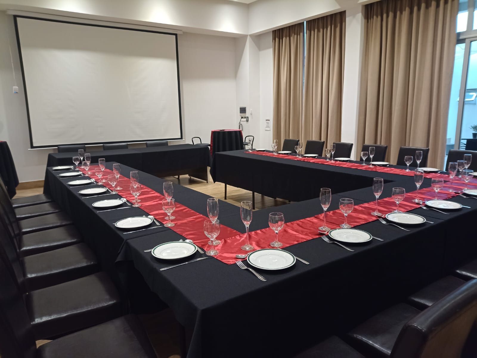 A conference room with tables and chairs and a projector screen.