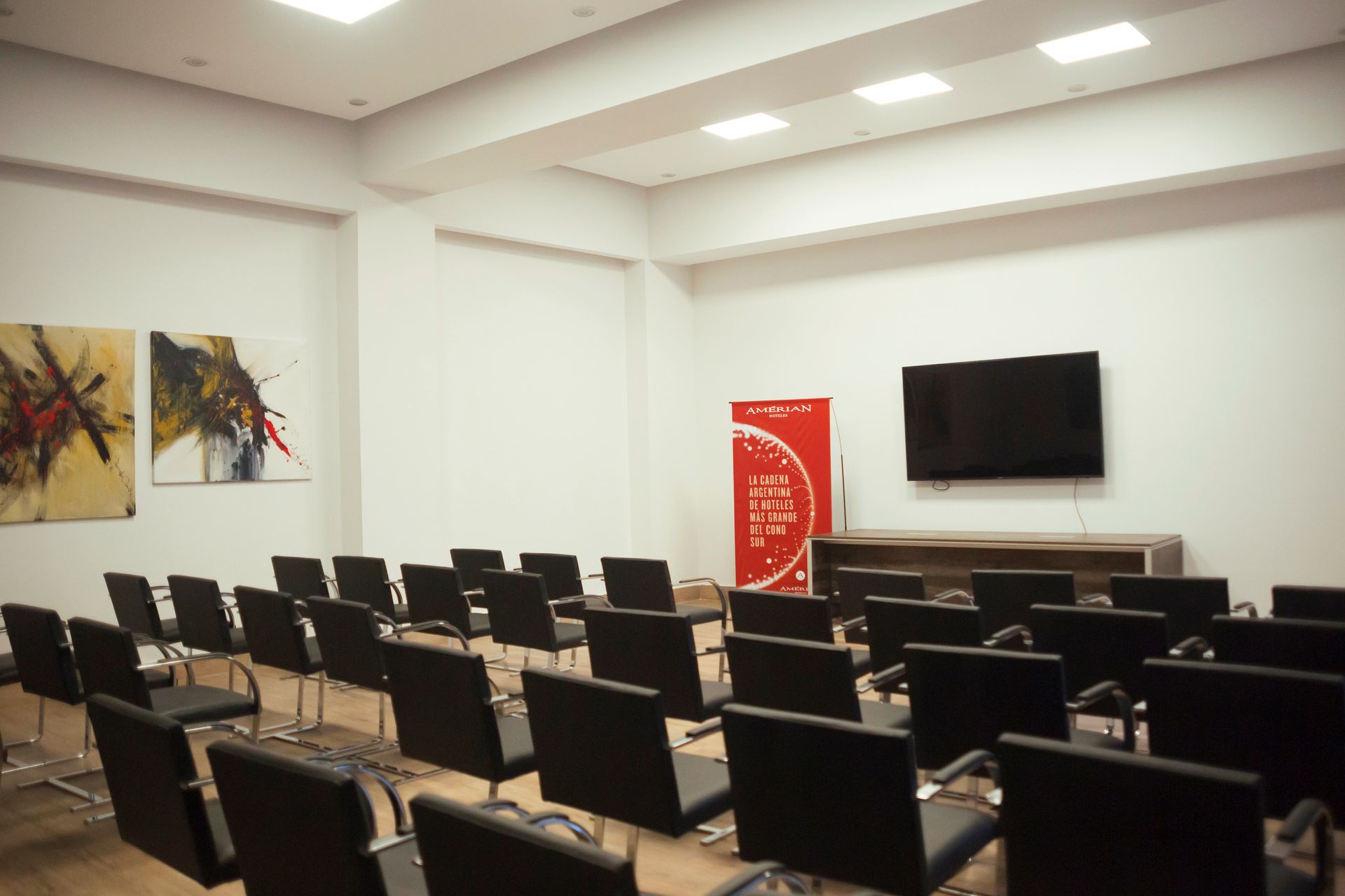 A conference room with rows of chairs and a flat screen tv.