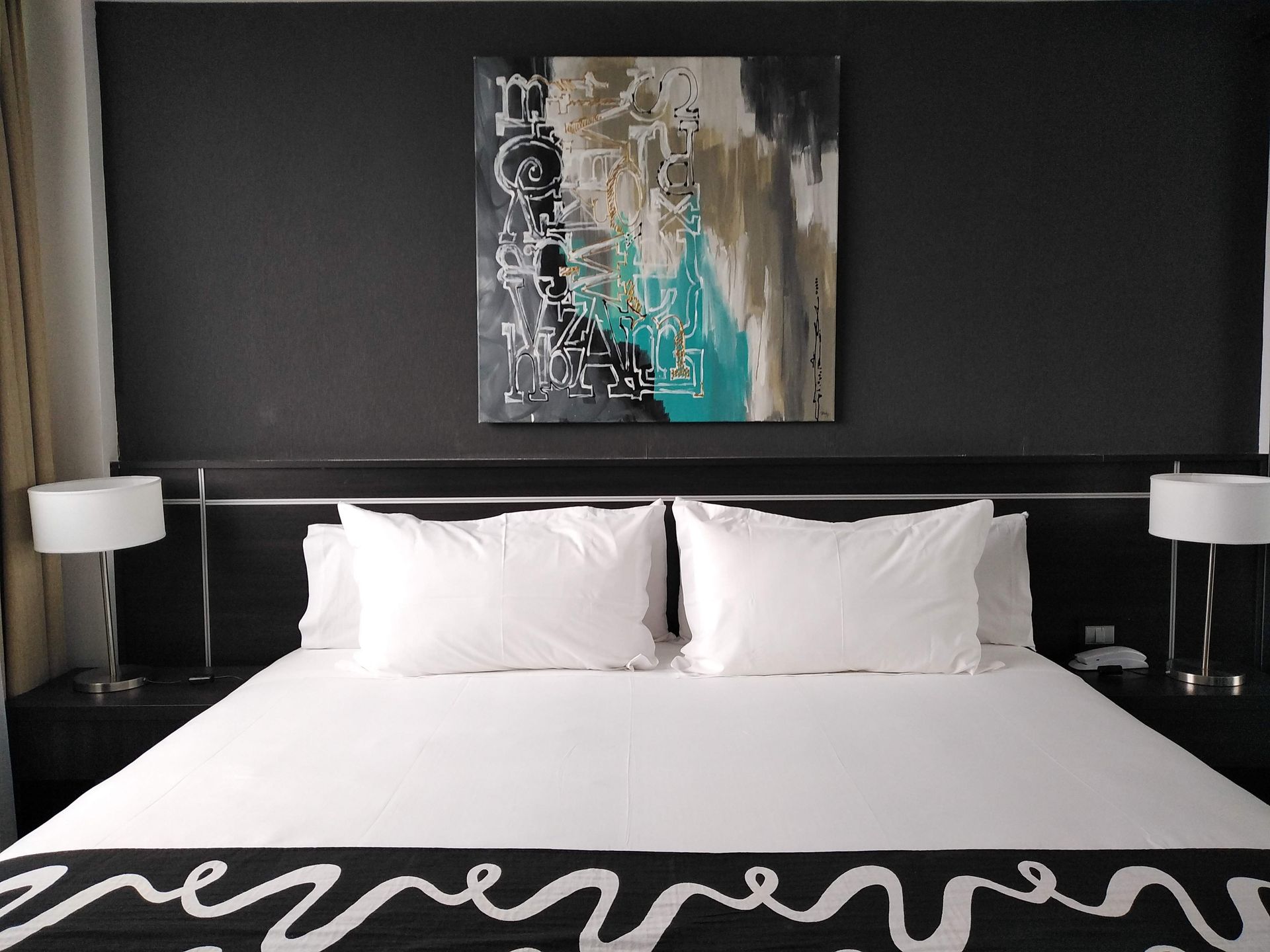 A hotel room with a bed and a painting on the wall