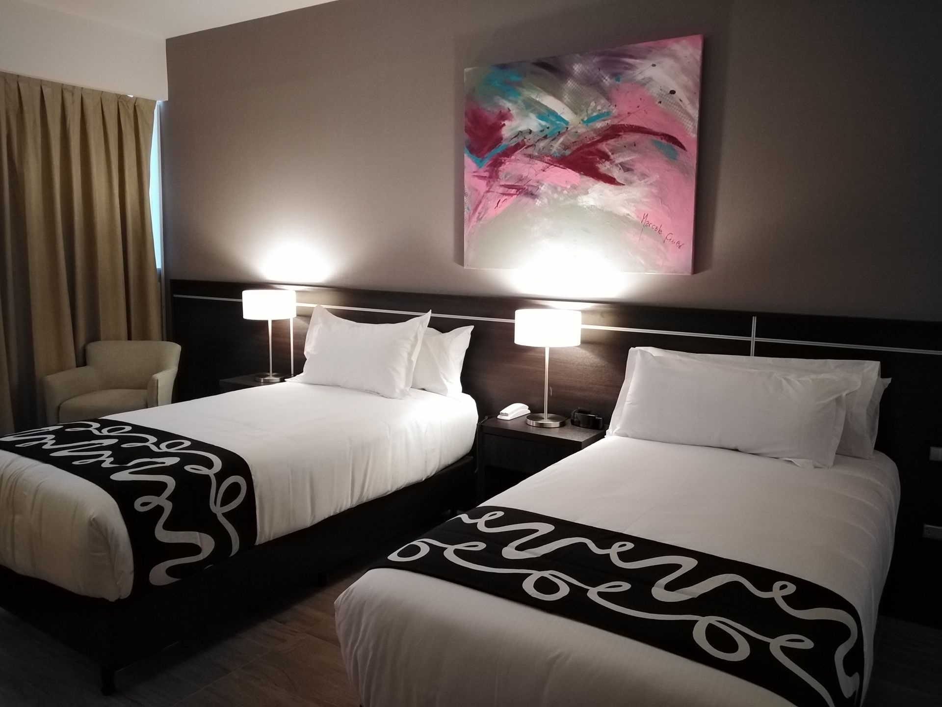 A hotel room with two beds and a painting on the wall