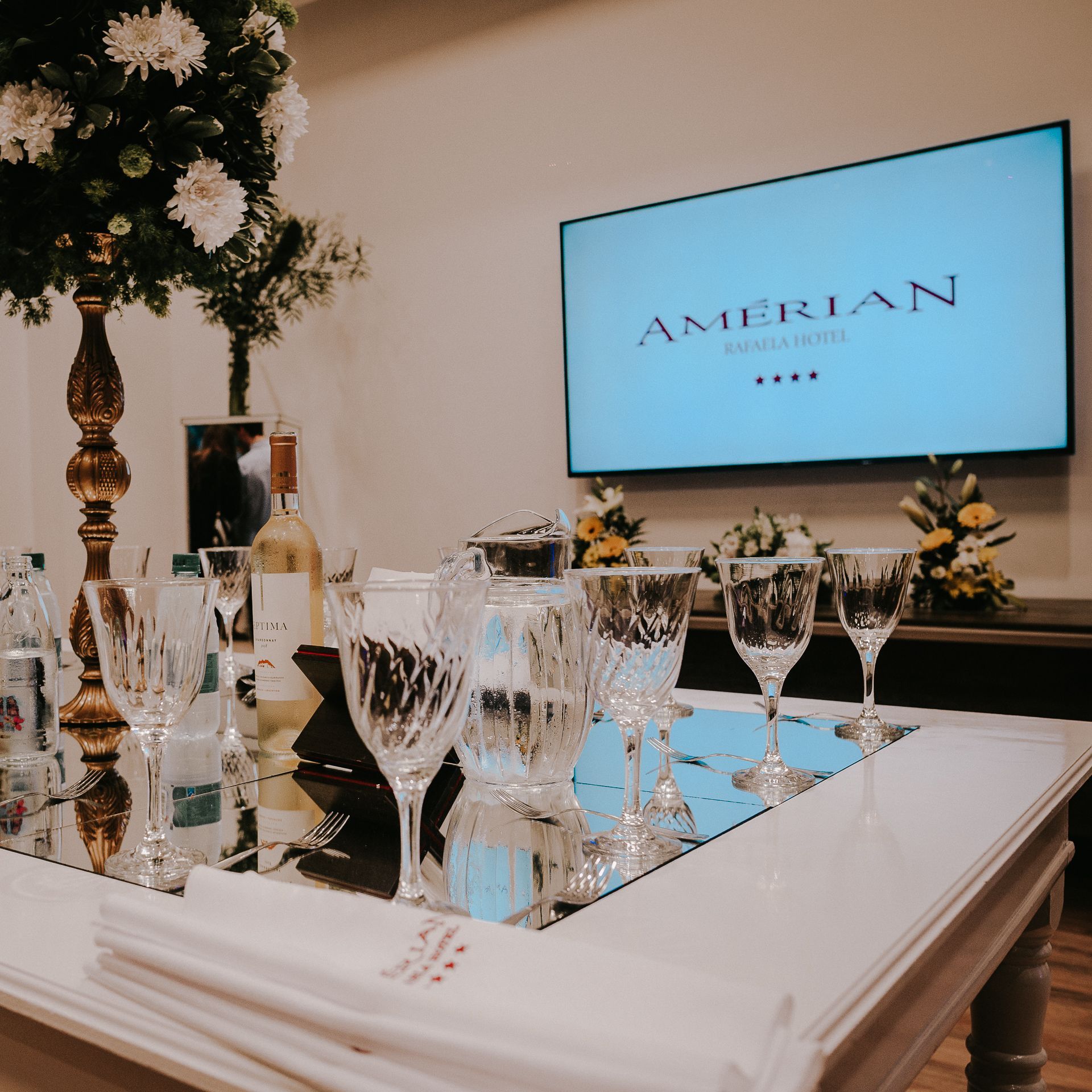 A table with wine glasses and a tv that says american on it