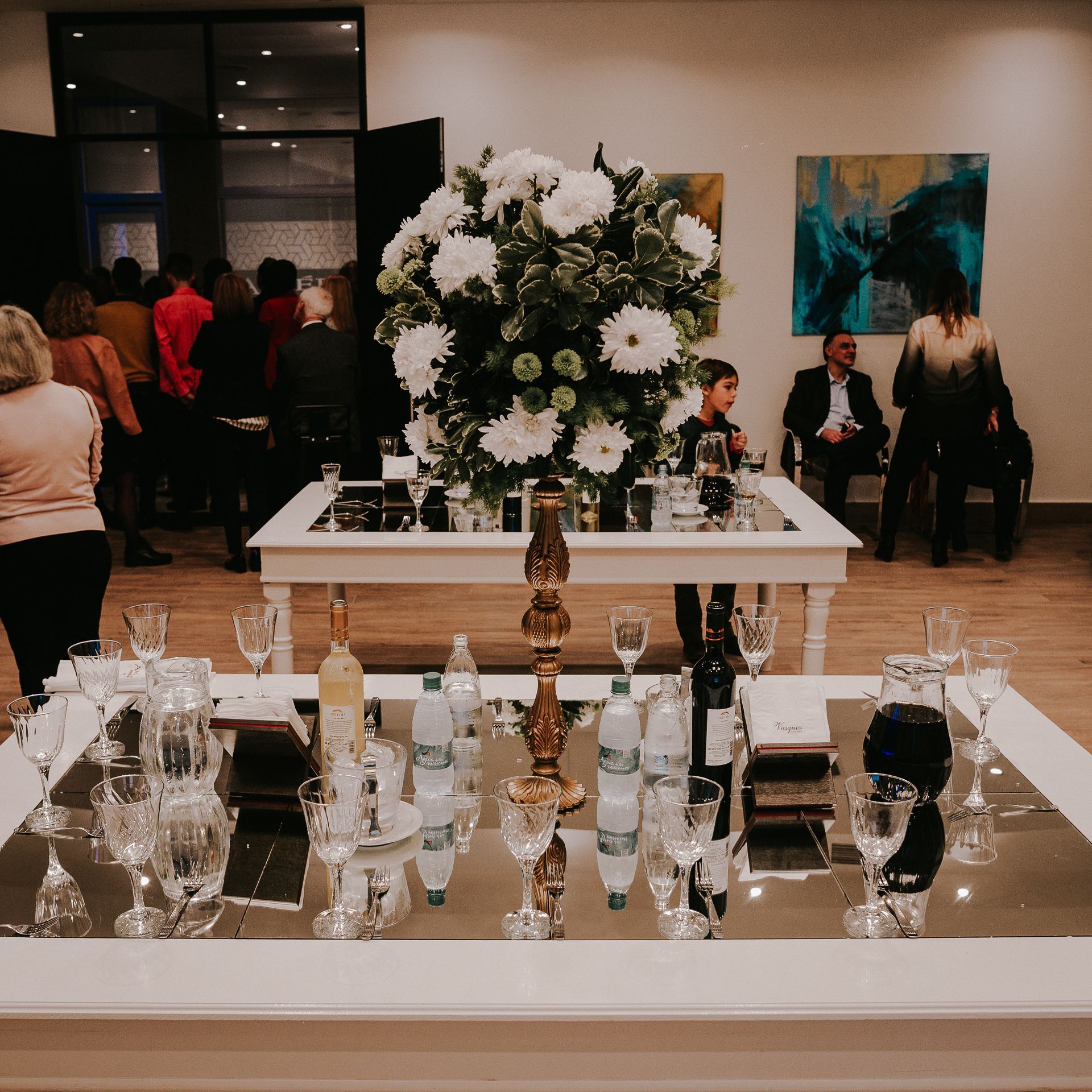 A table with a vase of flowers and wine glasses on it