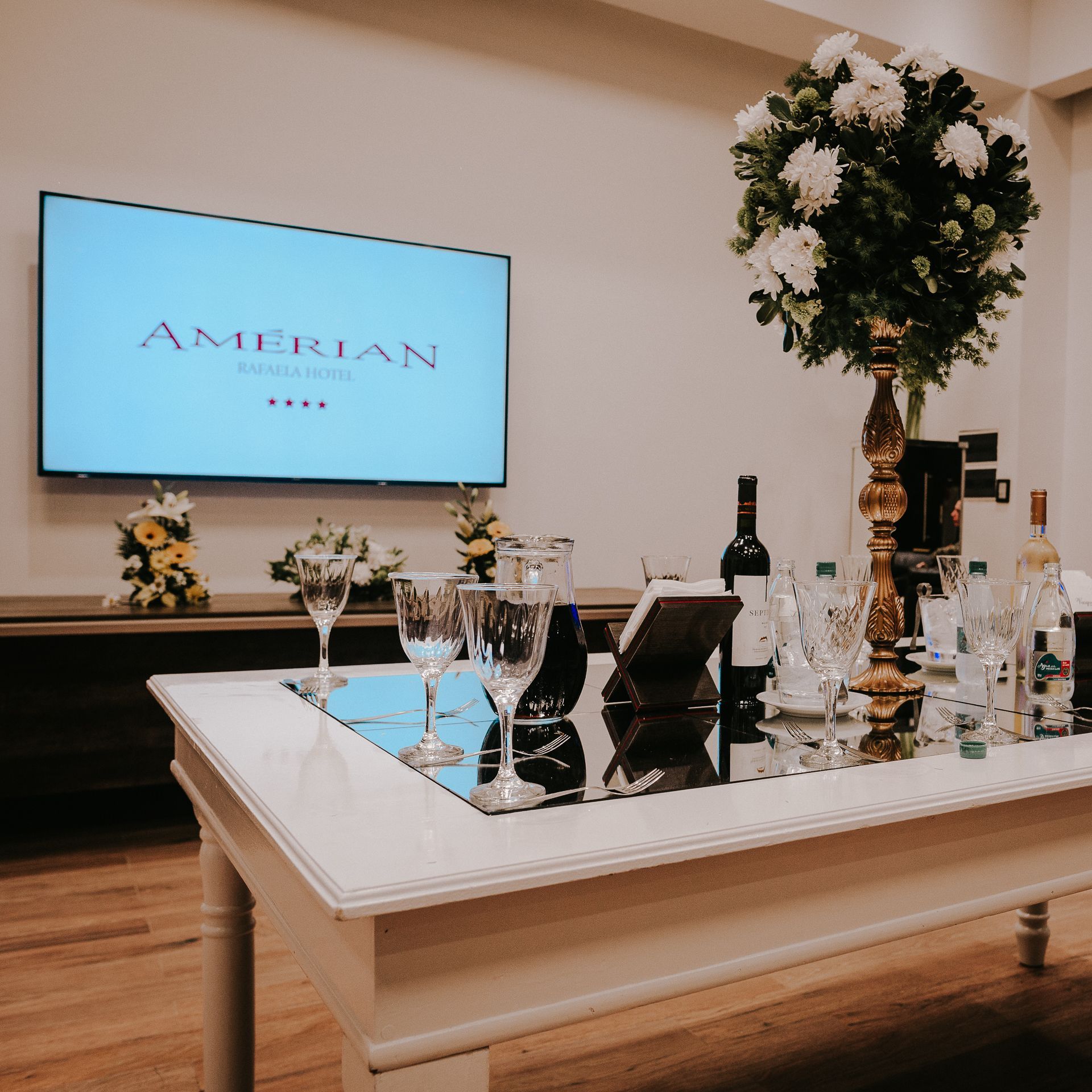 A table with wine glasses and a tv that says american on it
