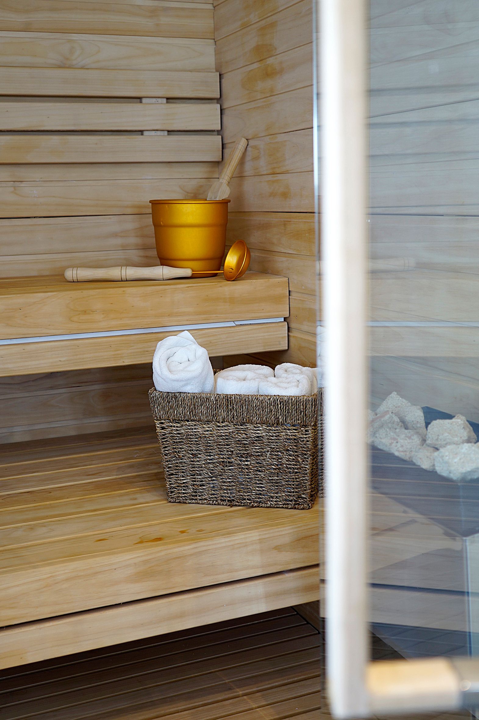 A wooden sauna with a basket of towels and a mortar and pestle.