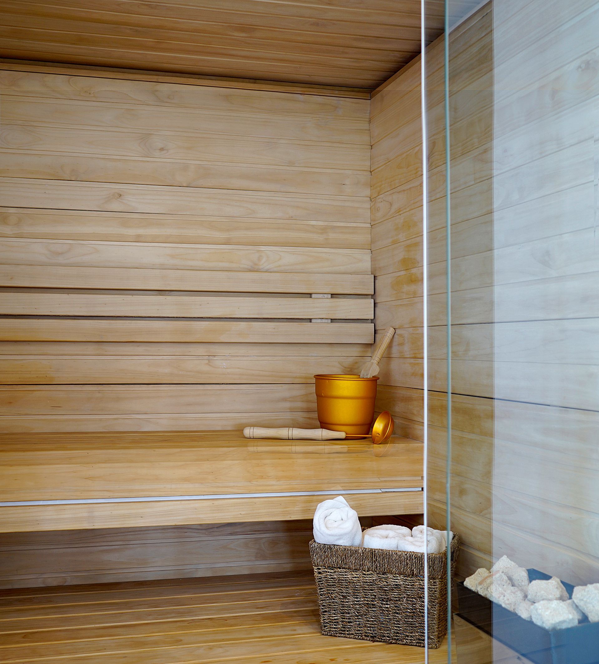 A wooden sauna with a bucket and a basket of towels